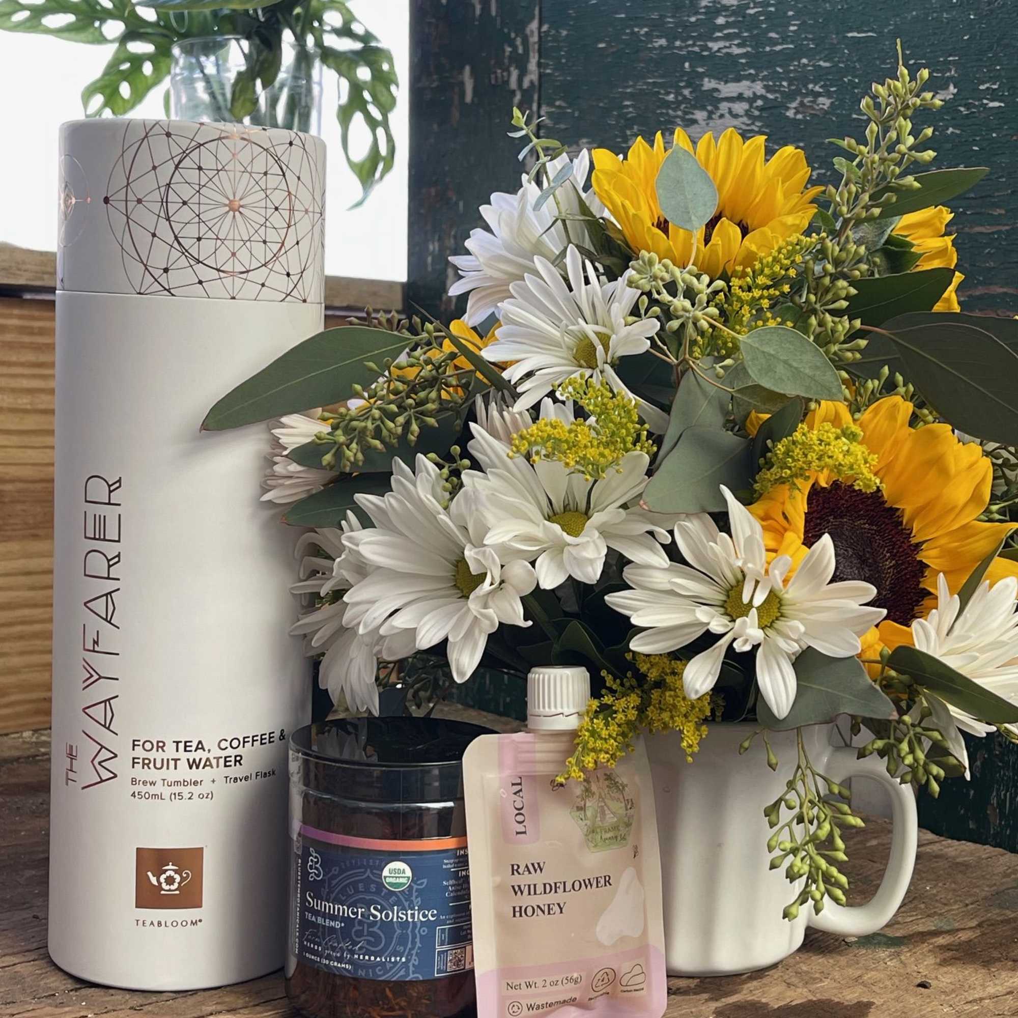 Bouquet of white daisies and yellow sunflowers in a white mug with gift items