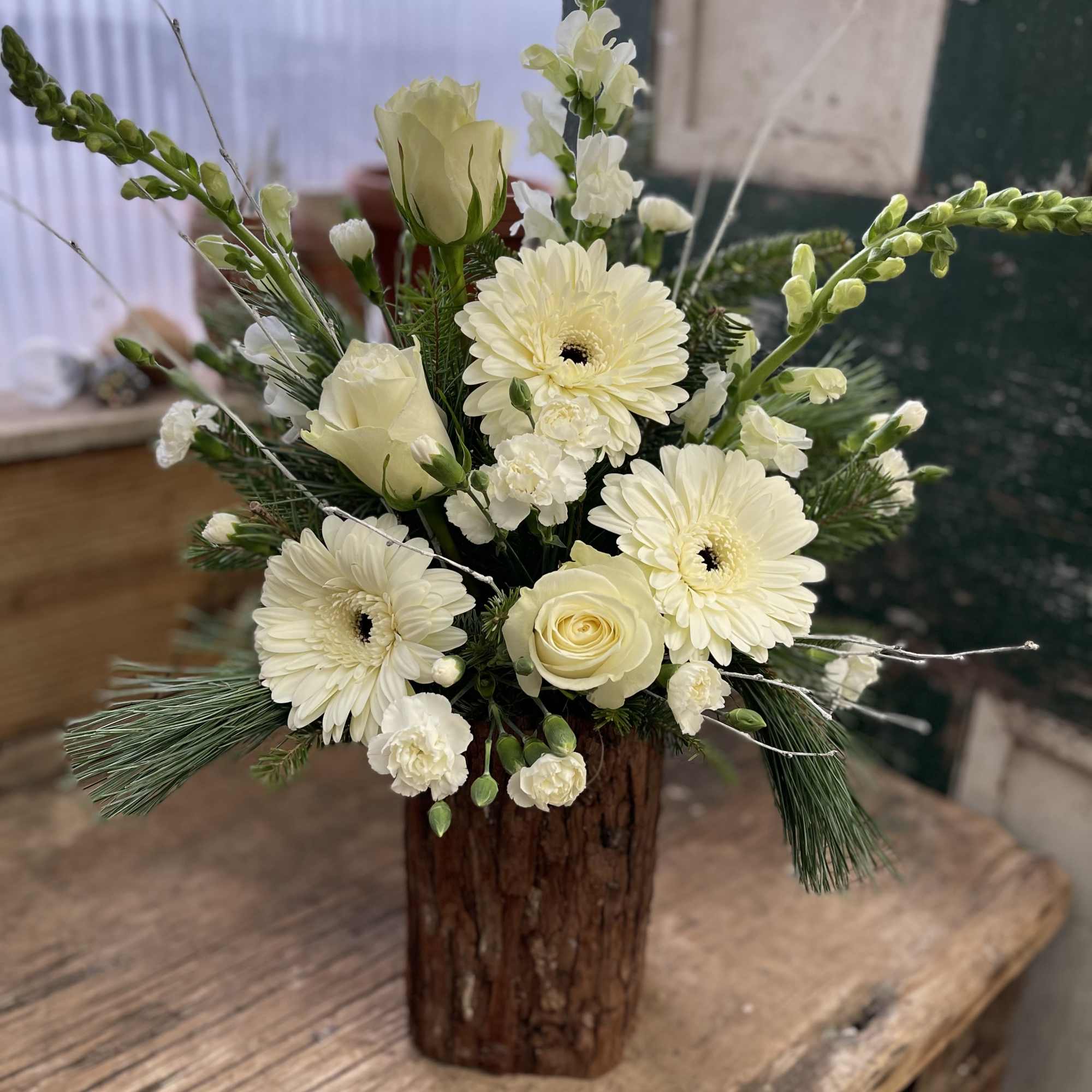 Cream floral arrangement in a rustic wooden vase