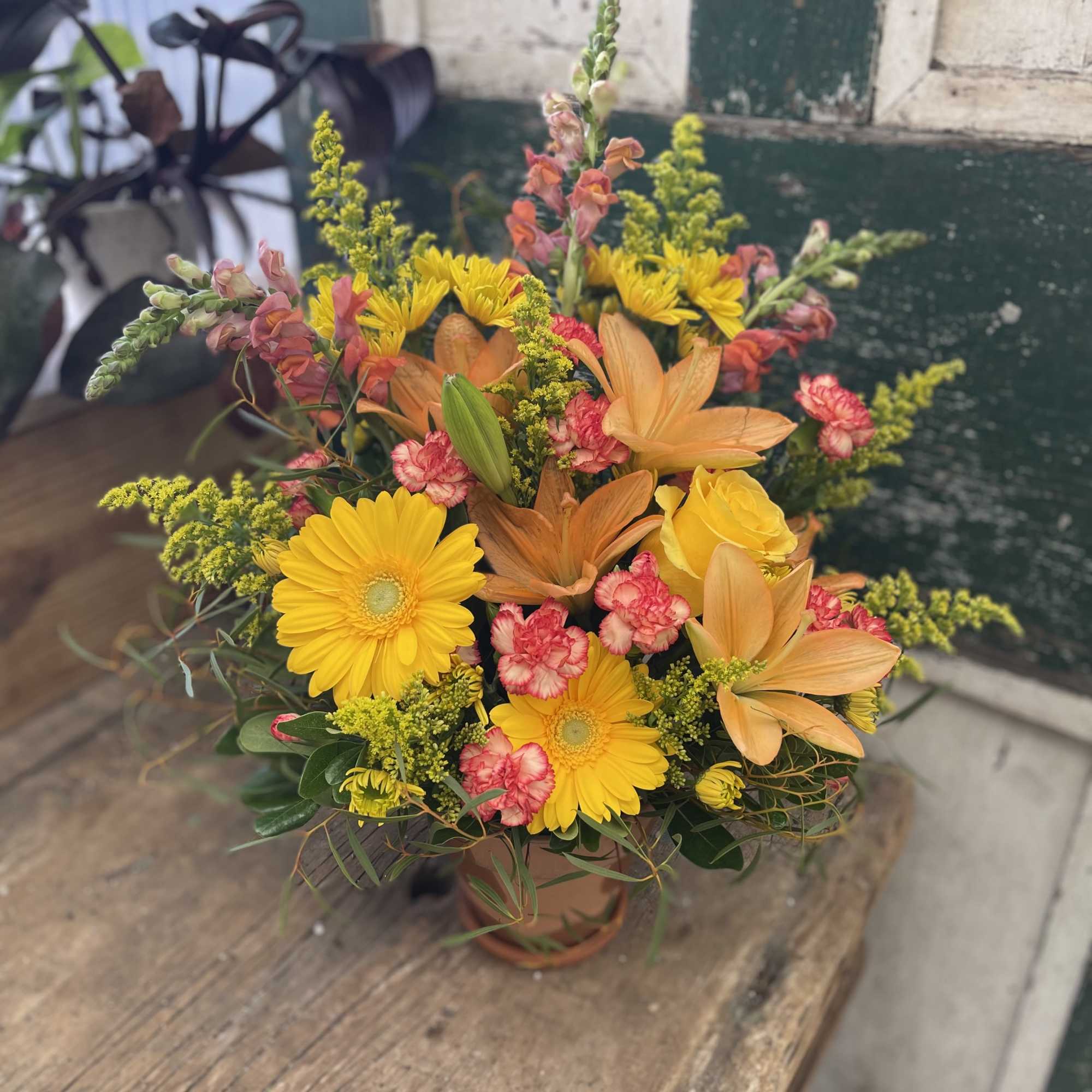 Mixed bouquet with yellow daisies, orange lilies, and pink carnations in a vase