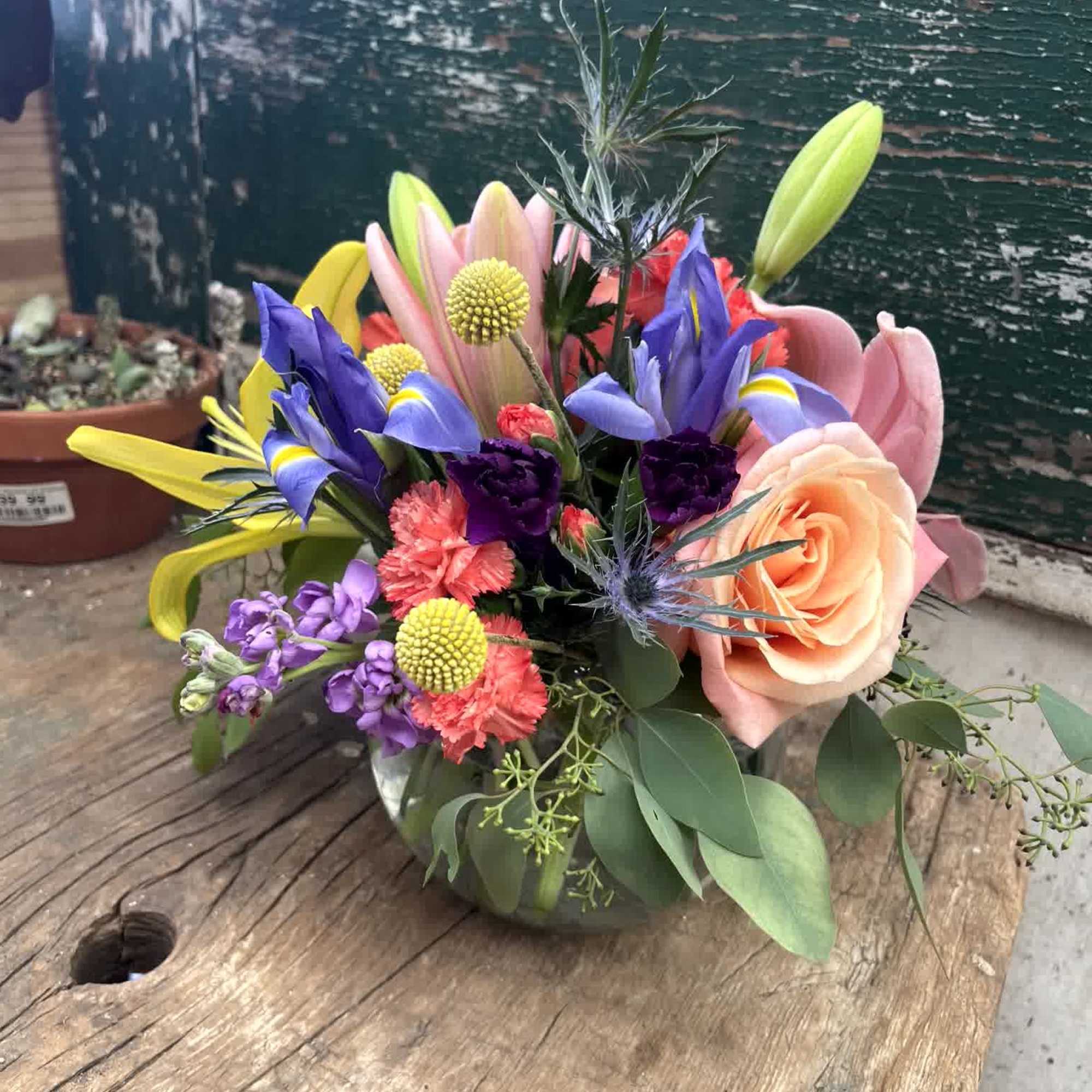 Colorful mixed bouquet with lilies, roses, and purple blooms in a glass vase