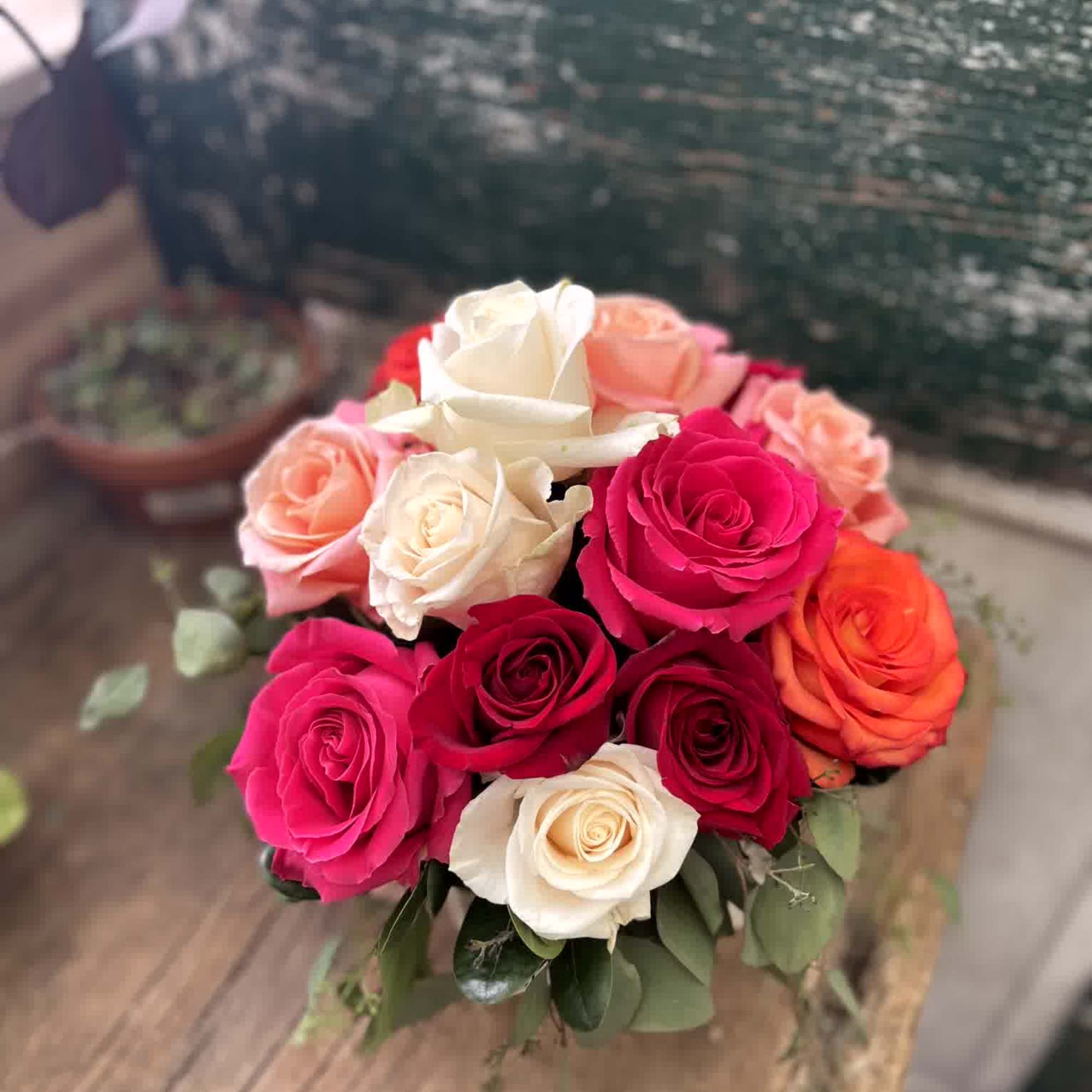 Bouquet of pink, red, orange, and white roses with greenery