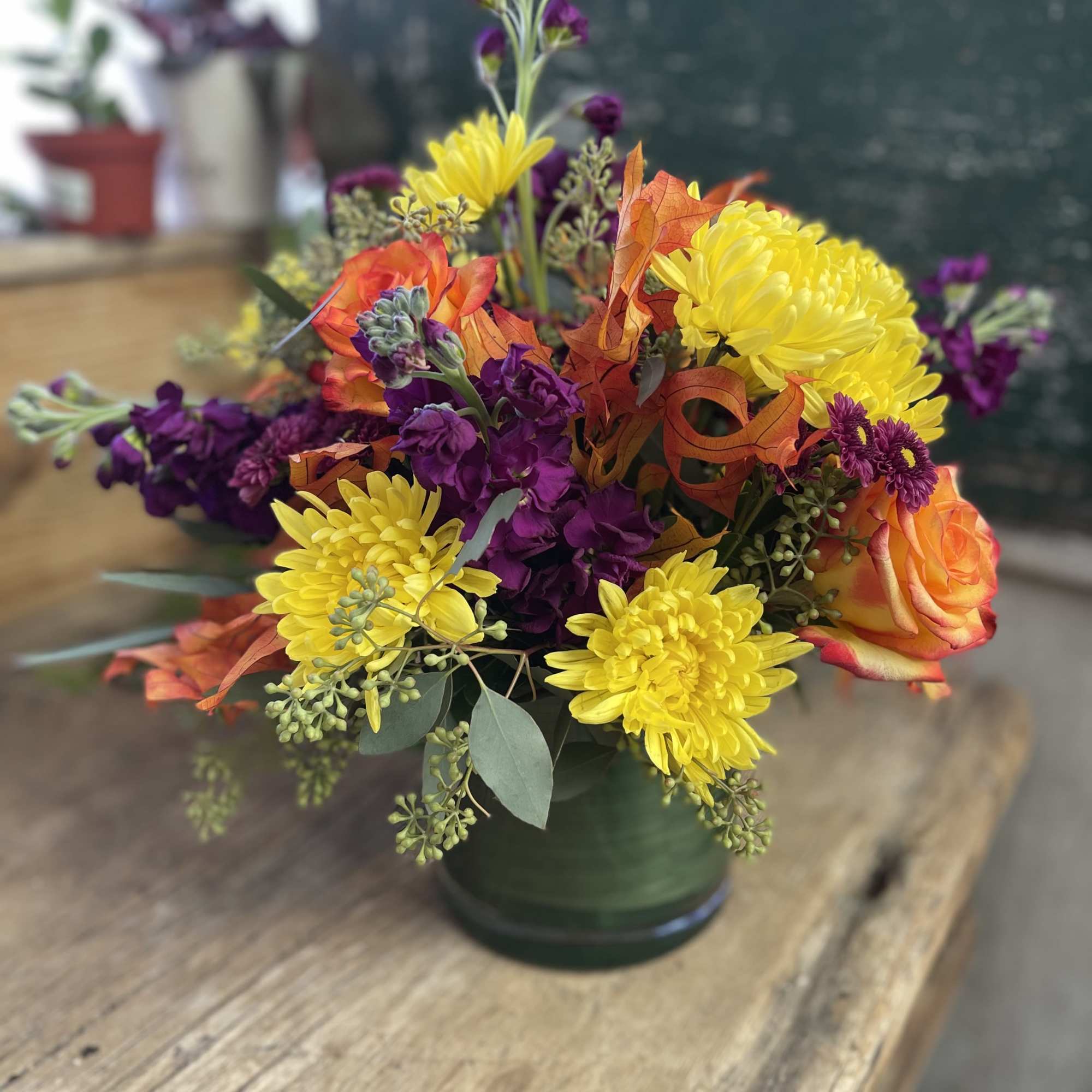 Bouquet of yellow chrysanthemums and orange roses in a green vase