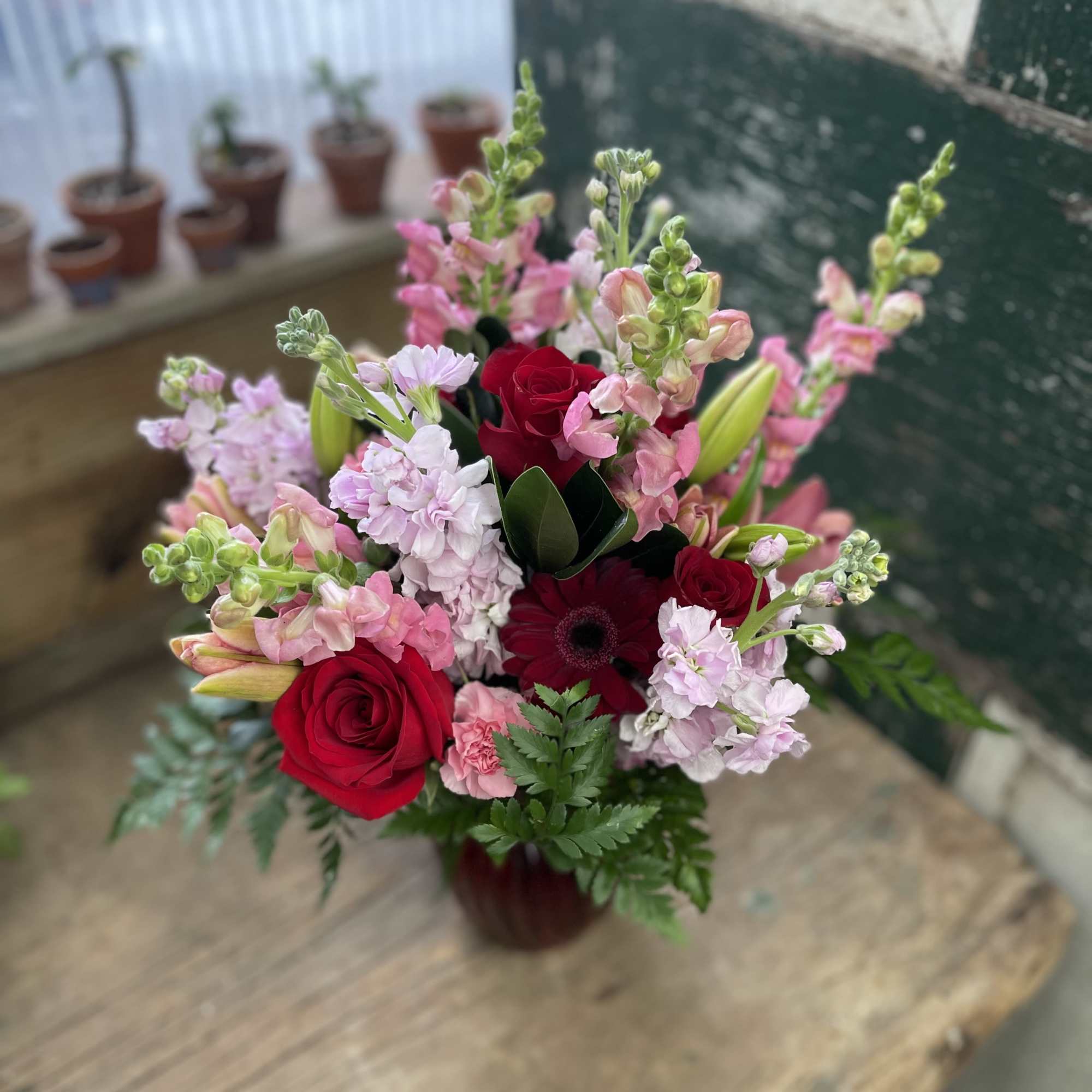 Bouquet of red roses, pink stock, and lilies in a vase