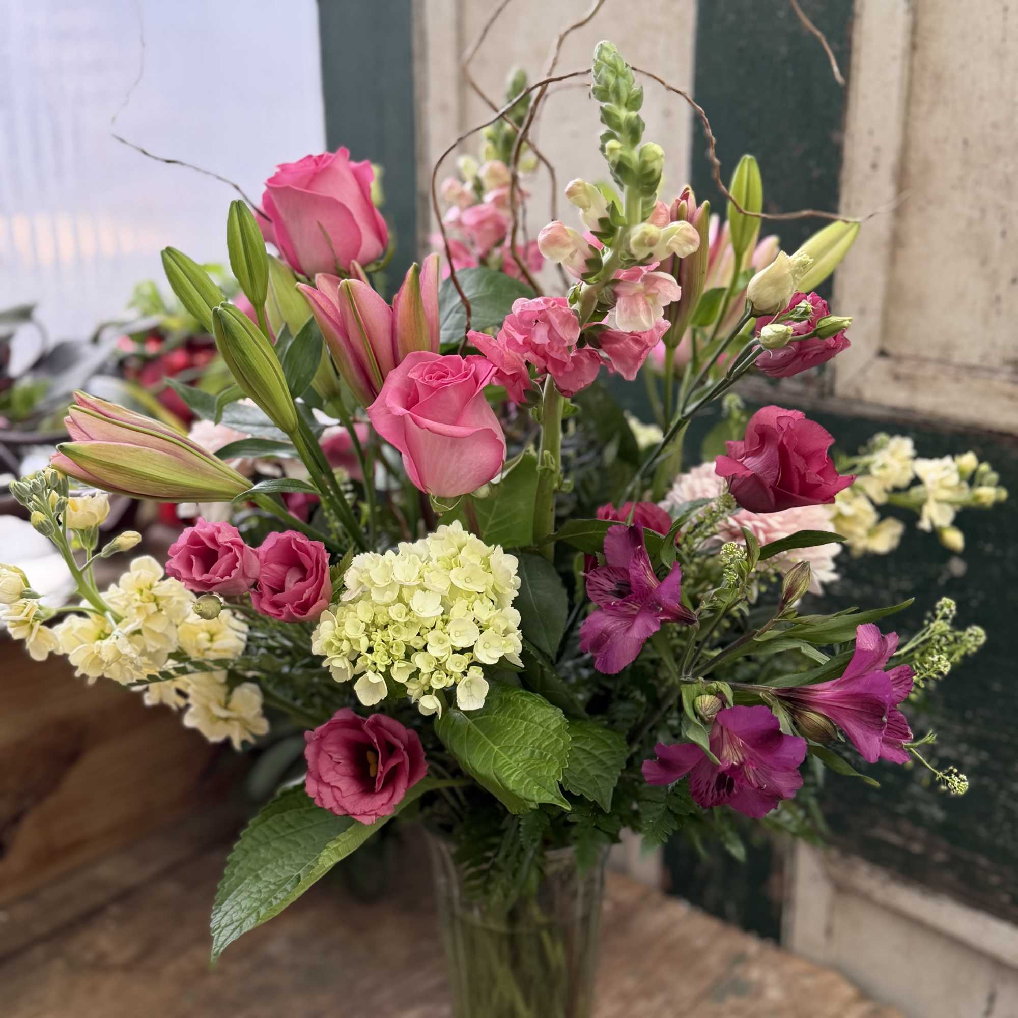 Pink roses and lilies arranged in a clear glass vase