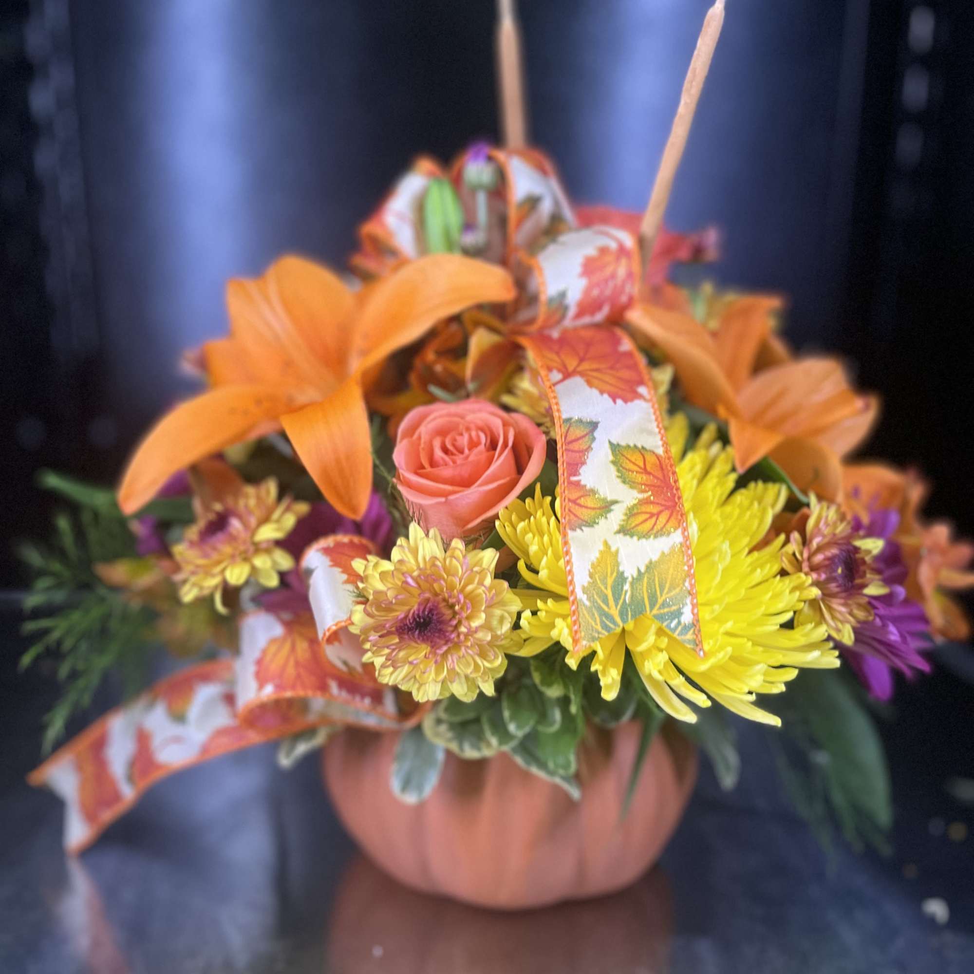 Orange and yellow floral basket with ribbon and a pink rose