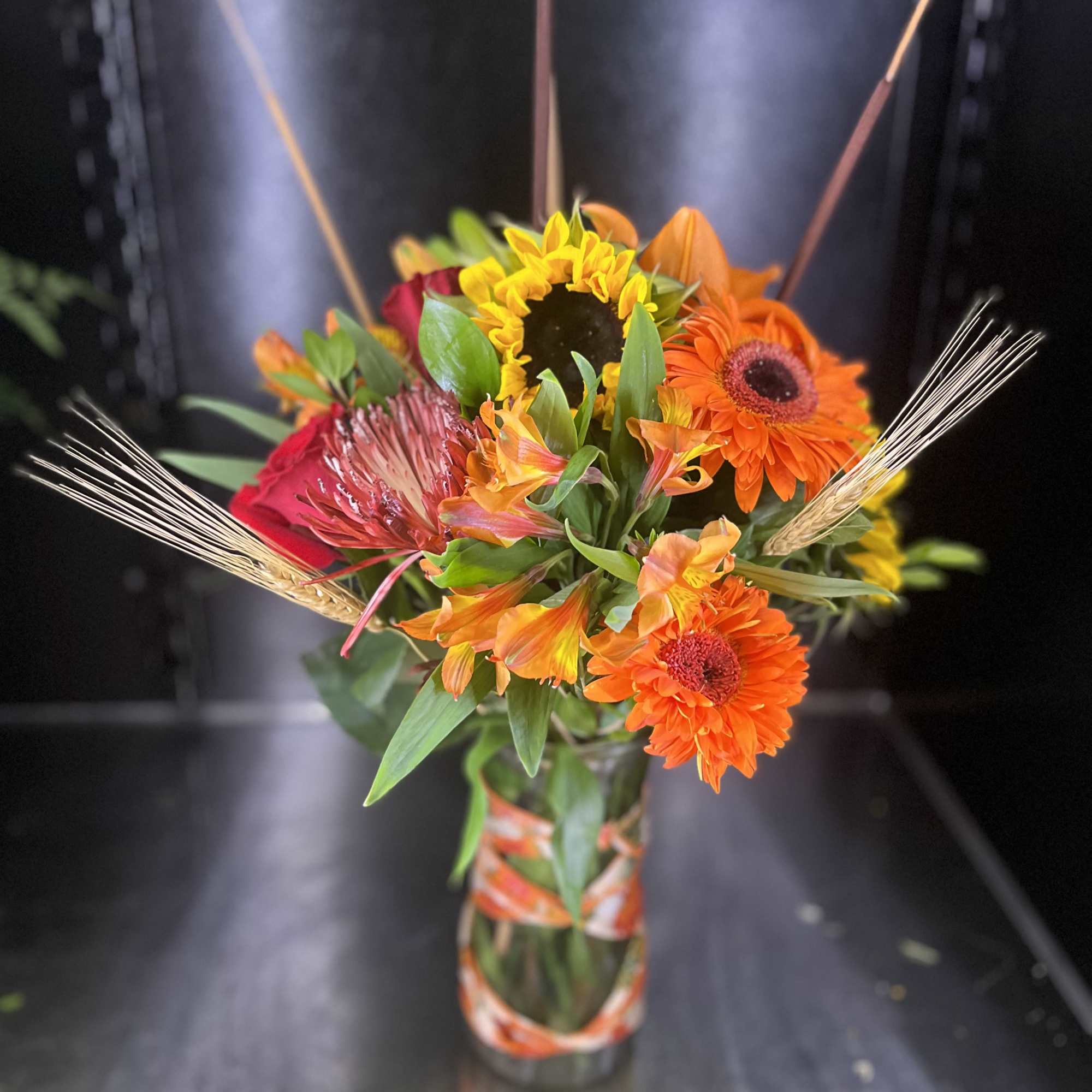 Bright mixed bouquet in a glass vase with orange and yellow blooms