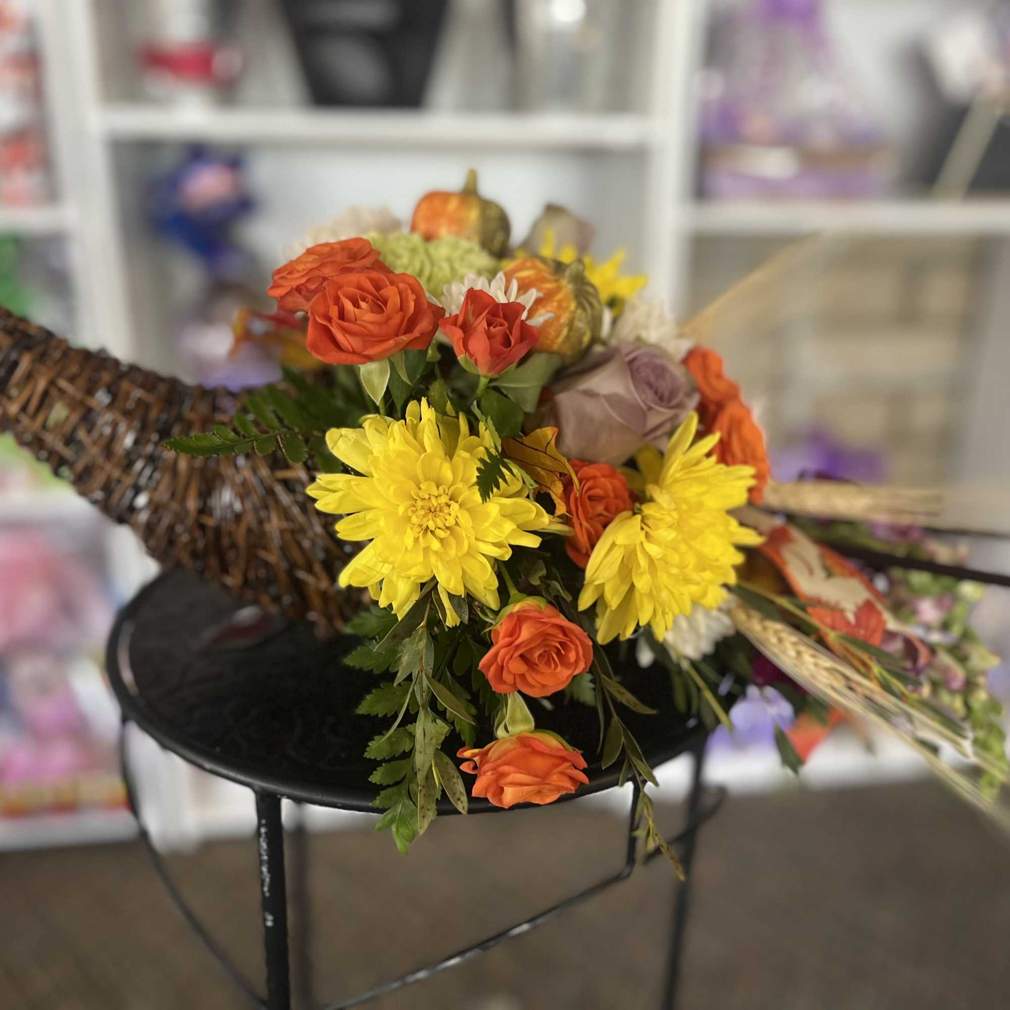 Cornucopia-style arrangement with orange roses and yellow daisies in a wicker horn