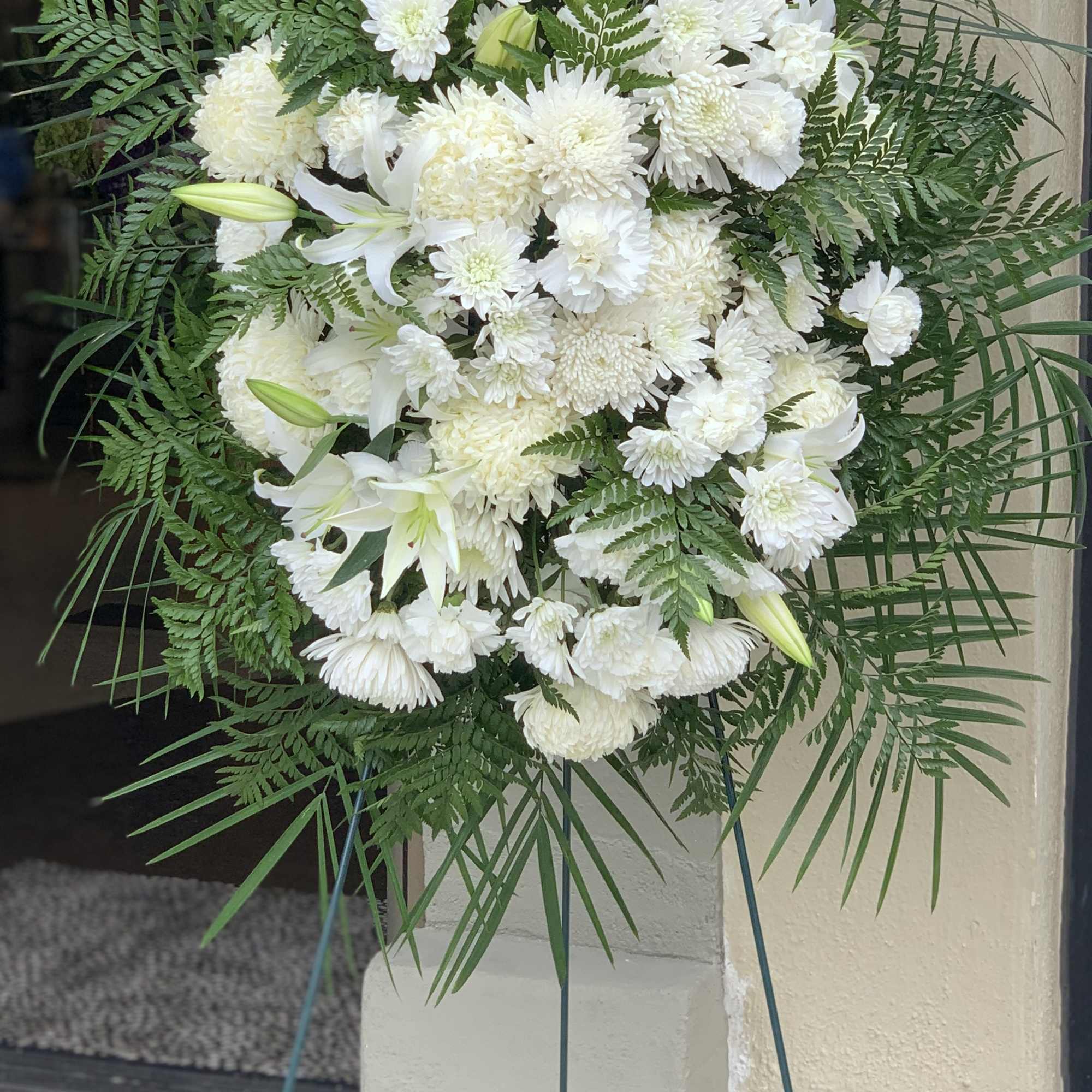 White funeral spray with lilies and chrysanthemums on a stand