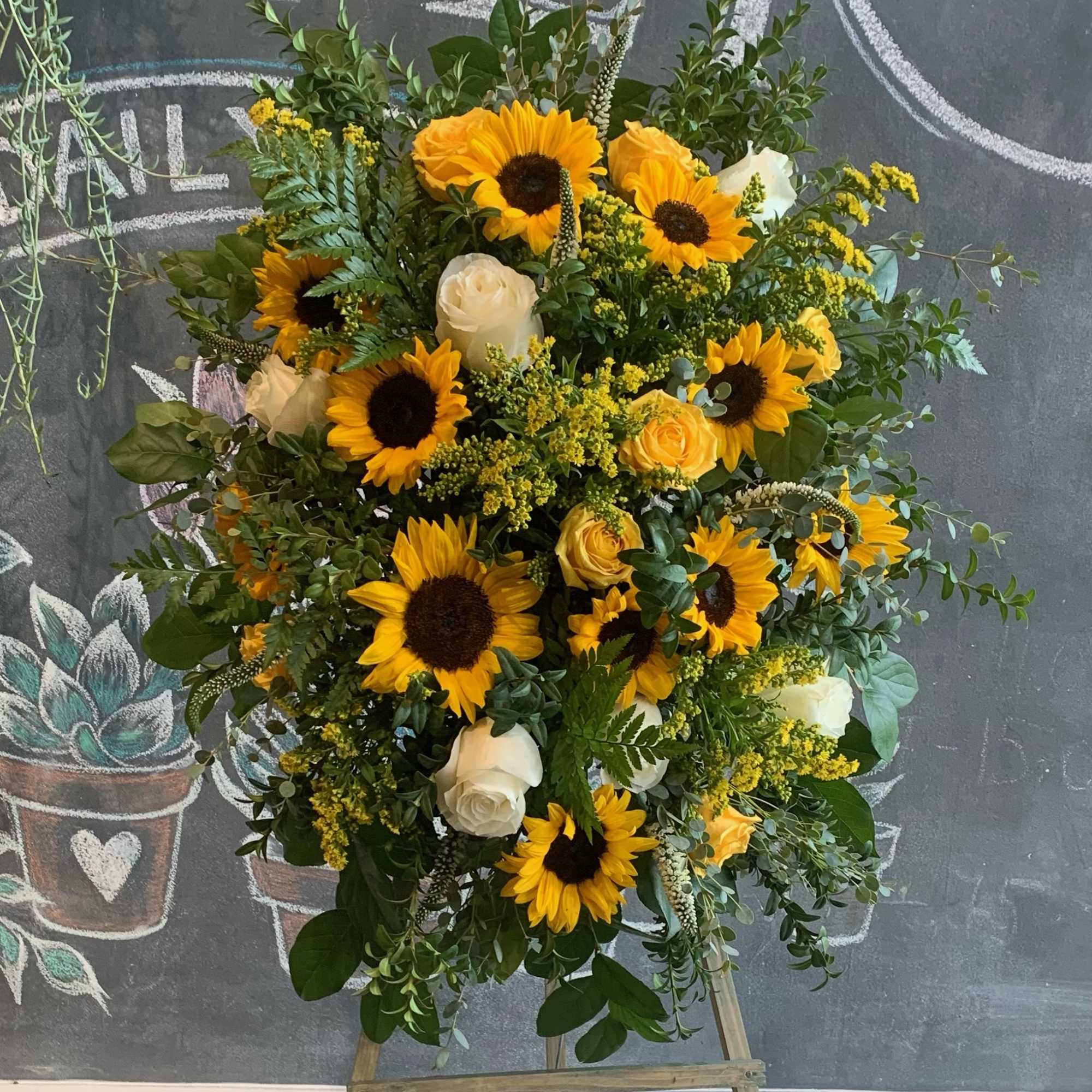 Large floral arrangement with sunflowers and white roses on an easel