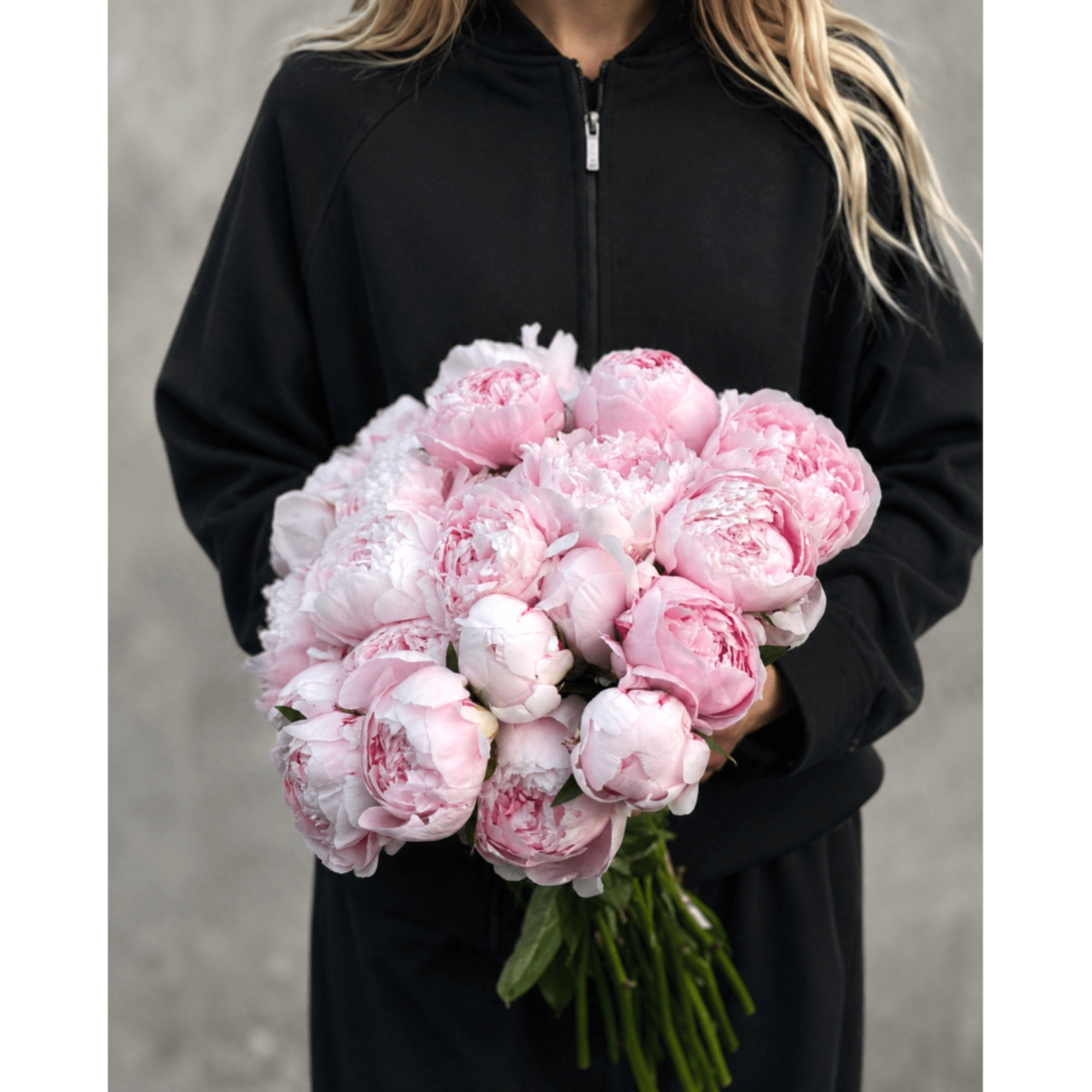 Person holding a bouquet of pale pink peonies