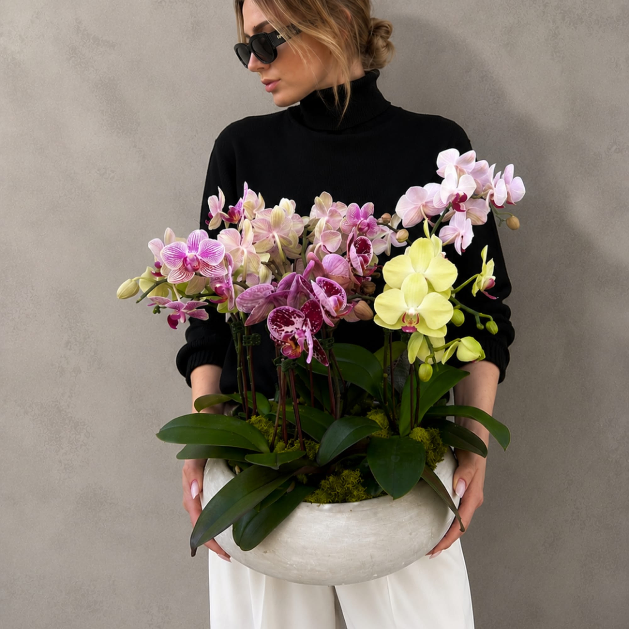 Woman holding a large bowl of pink and yellow orchids