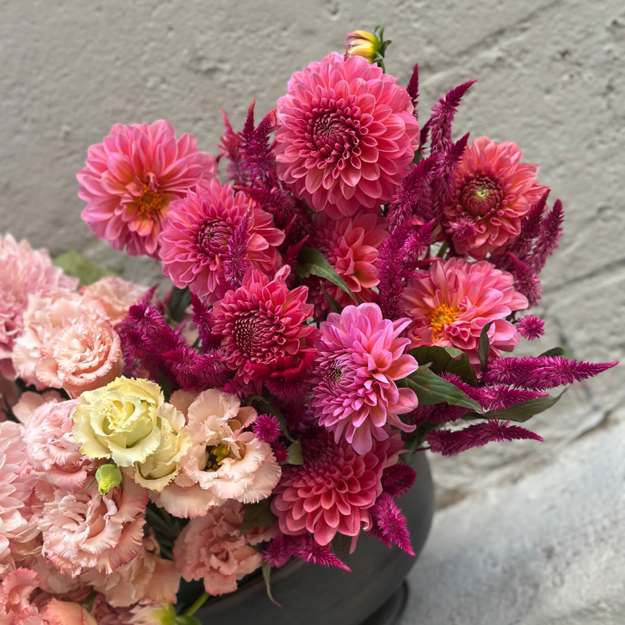 Pink and peach flowers arranged in a dark vase