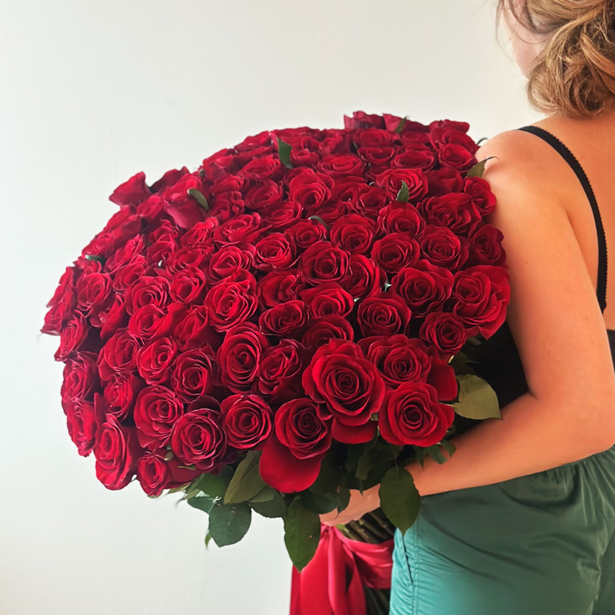 Large bouquet of red roses held by a woman