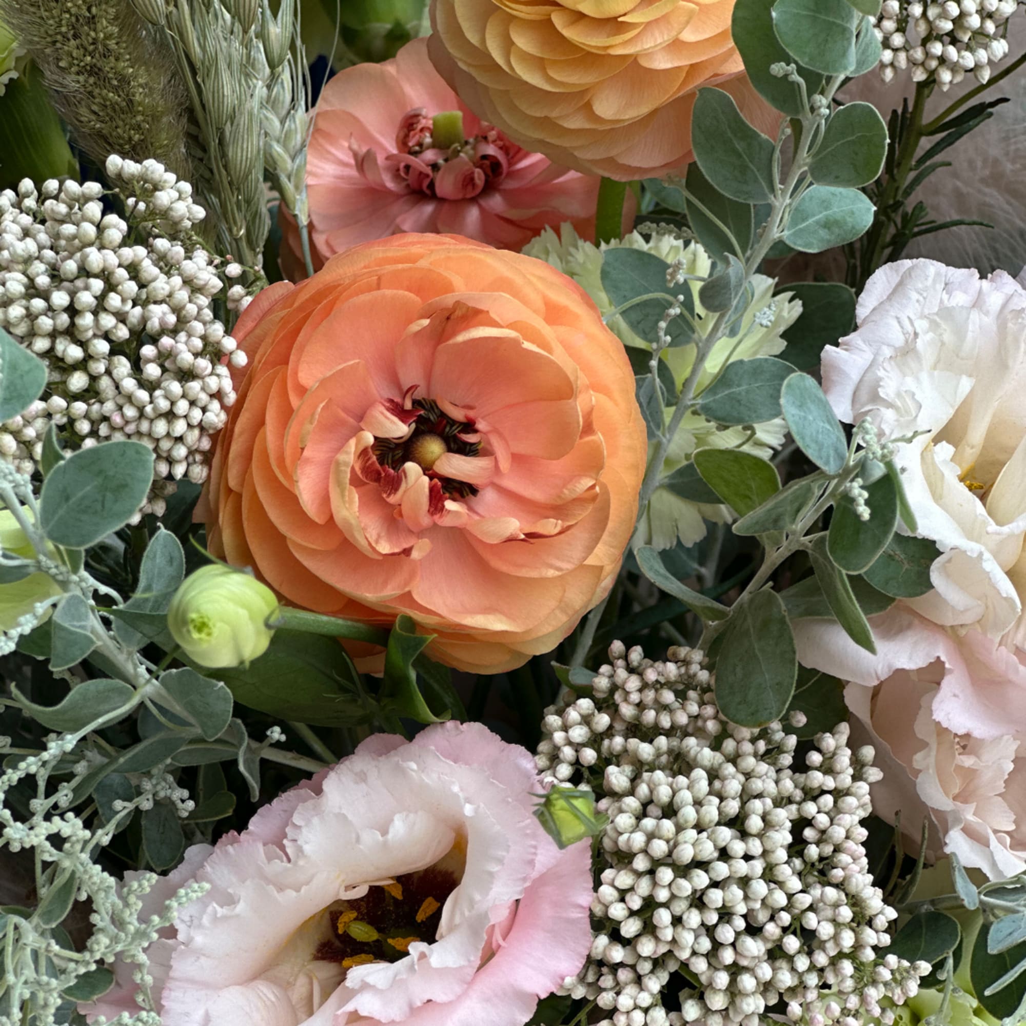 Close-up bouquet with peach ranunculus and pale pink lisianthus