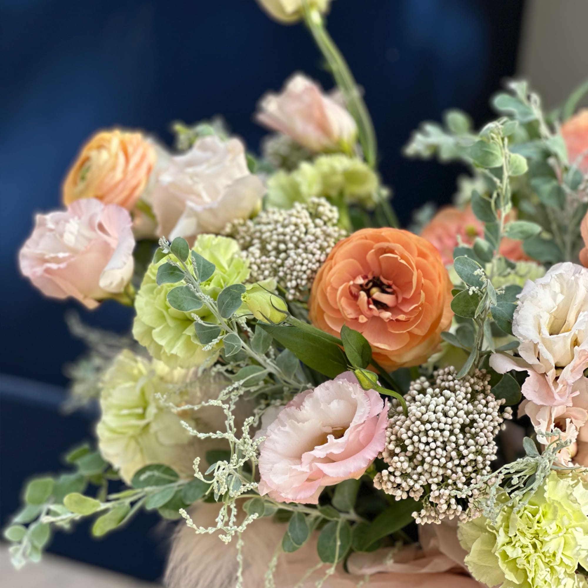Pastel bouquet with peach, pink, and green flowers in a wrapped arrangement