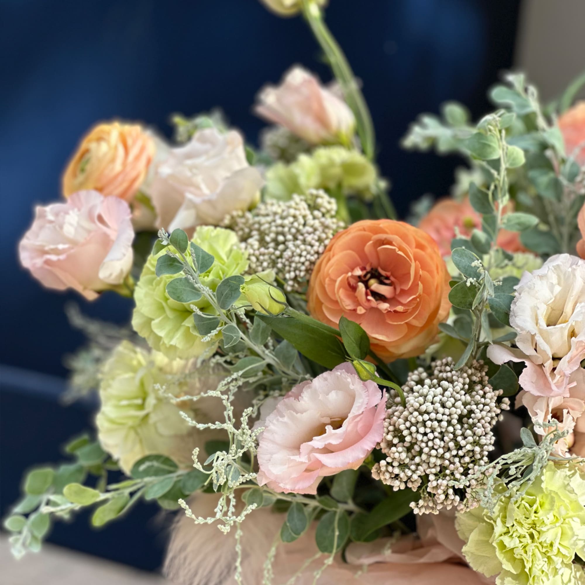 Pastel bouquet with peach, pink, and green blooms in a wrapped arrangement