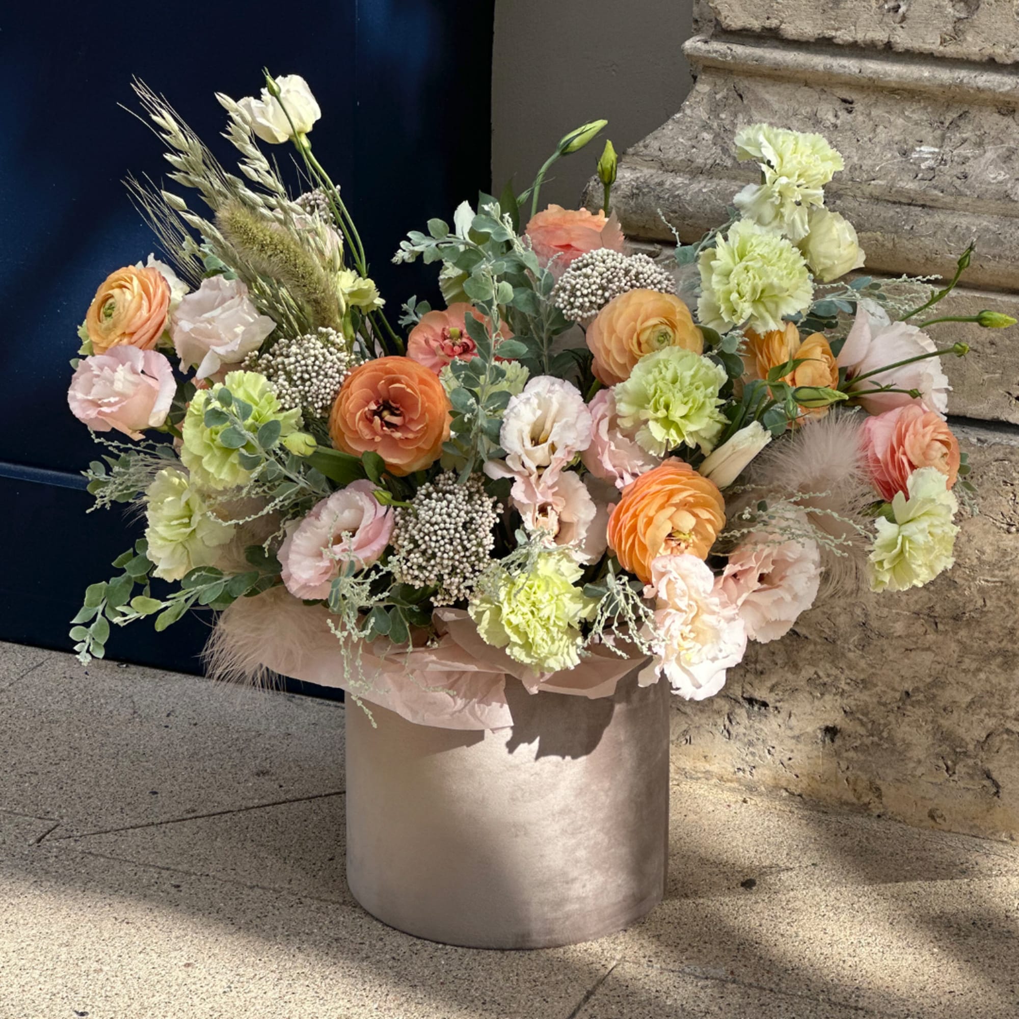 Pastel floral arrangement in a round metallic vase with peach, pink, and cream blooms