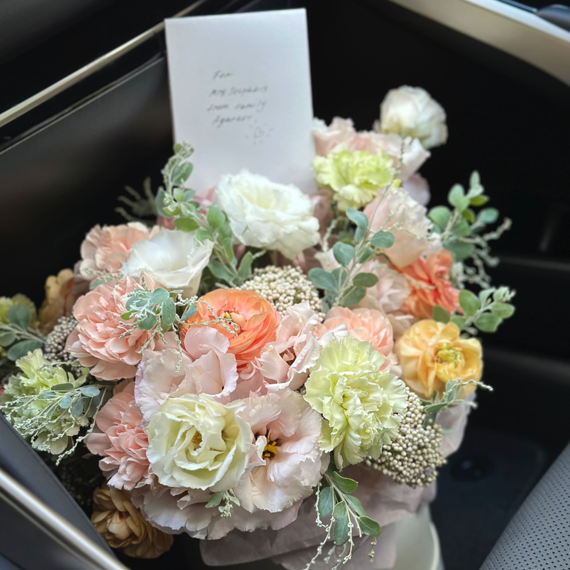 Pastel bouquet of mixed flowers with a note card in a black box