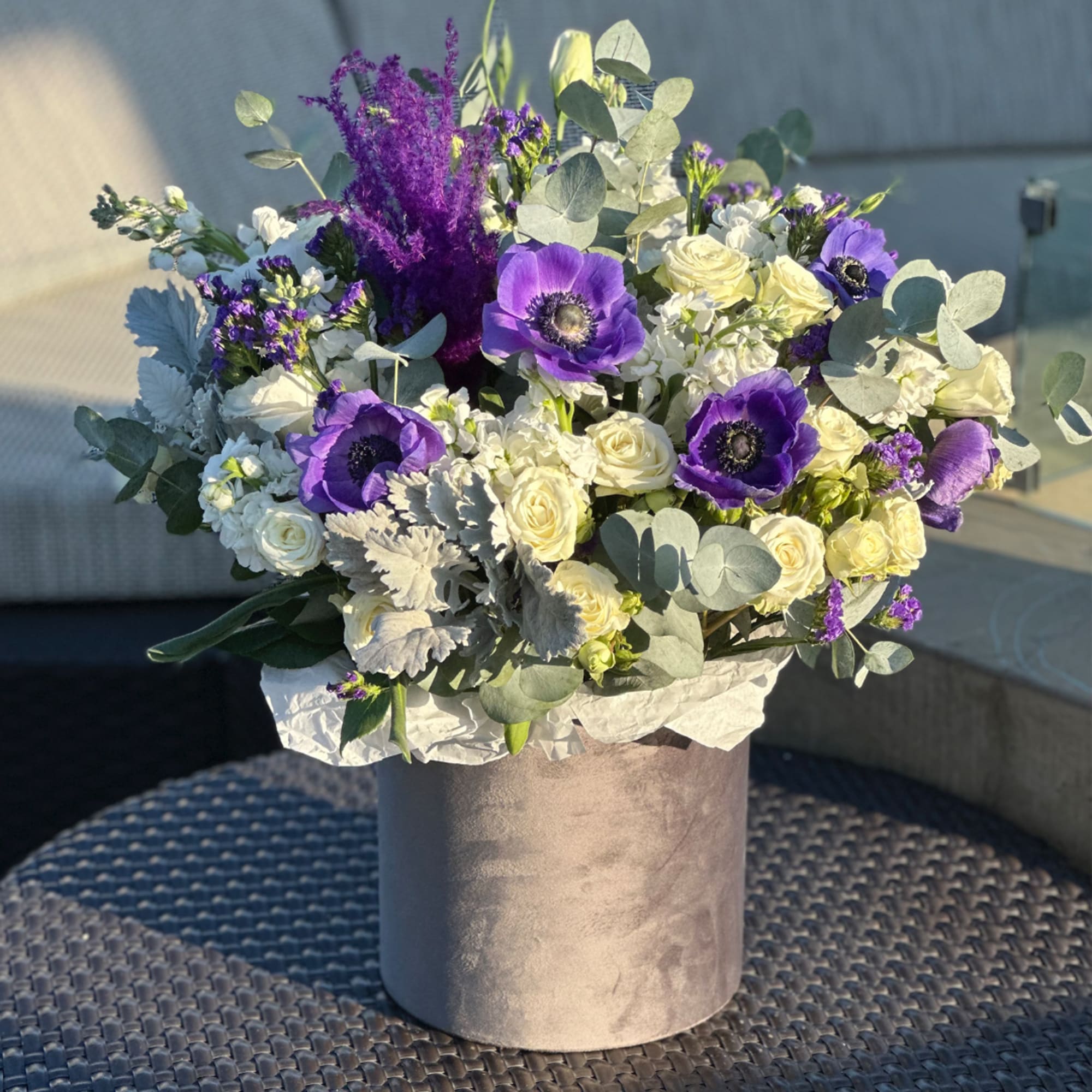 Purple and white flowers arranged in a round hatbox