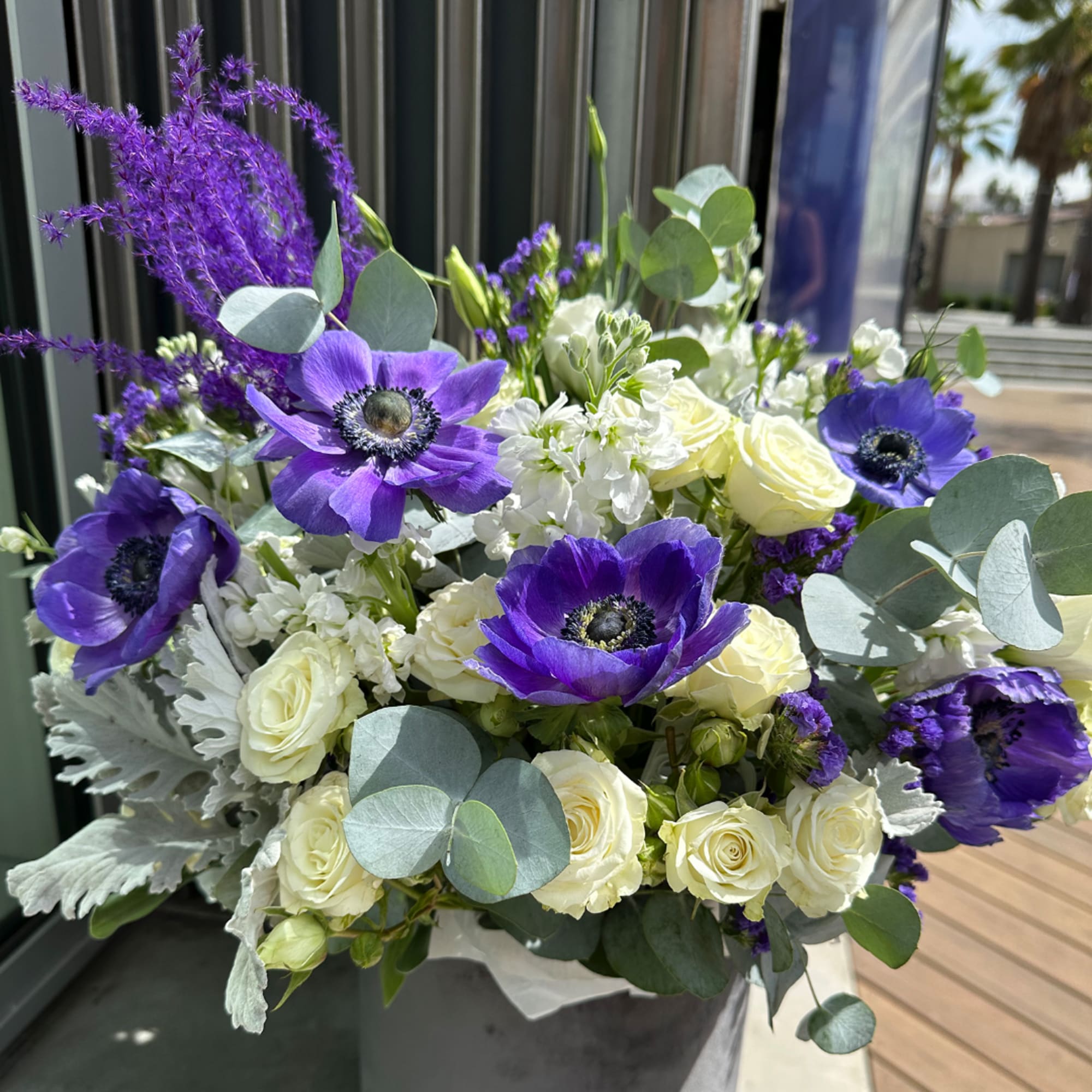 Purple anemones and white roses in a vase with eucalyptus