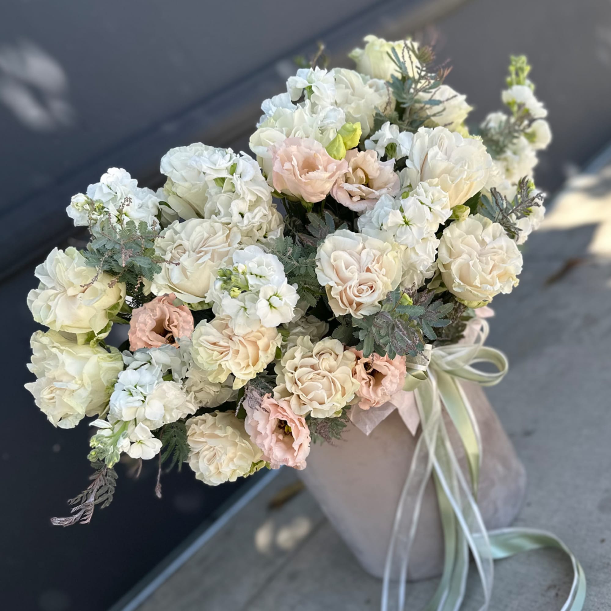 Bouquet of cream and blush roses in a wrapped vase with ribbon