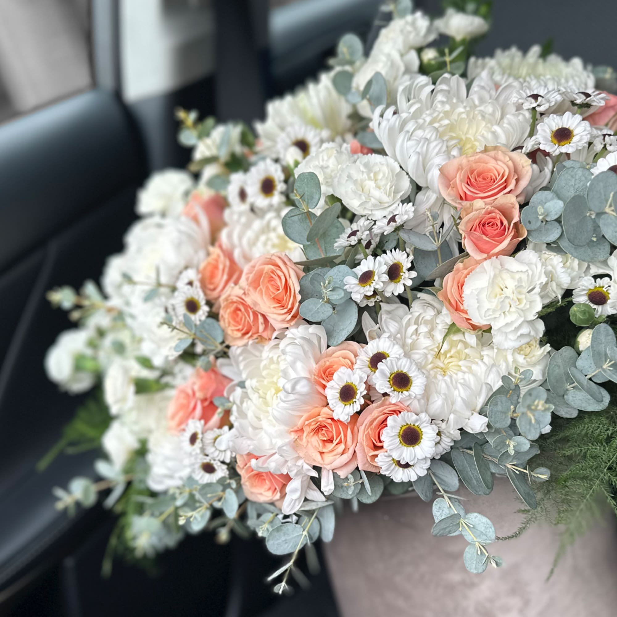 Bouquet of peach roses and white daisies with white blooms and blue-green foliage