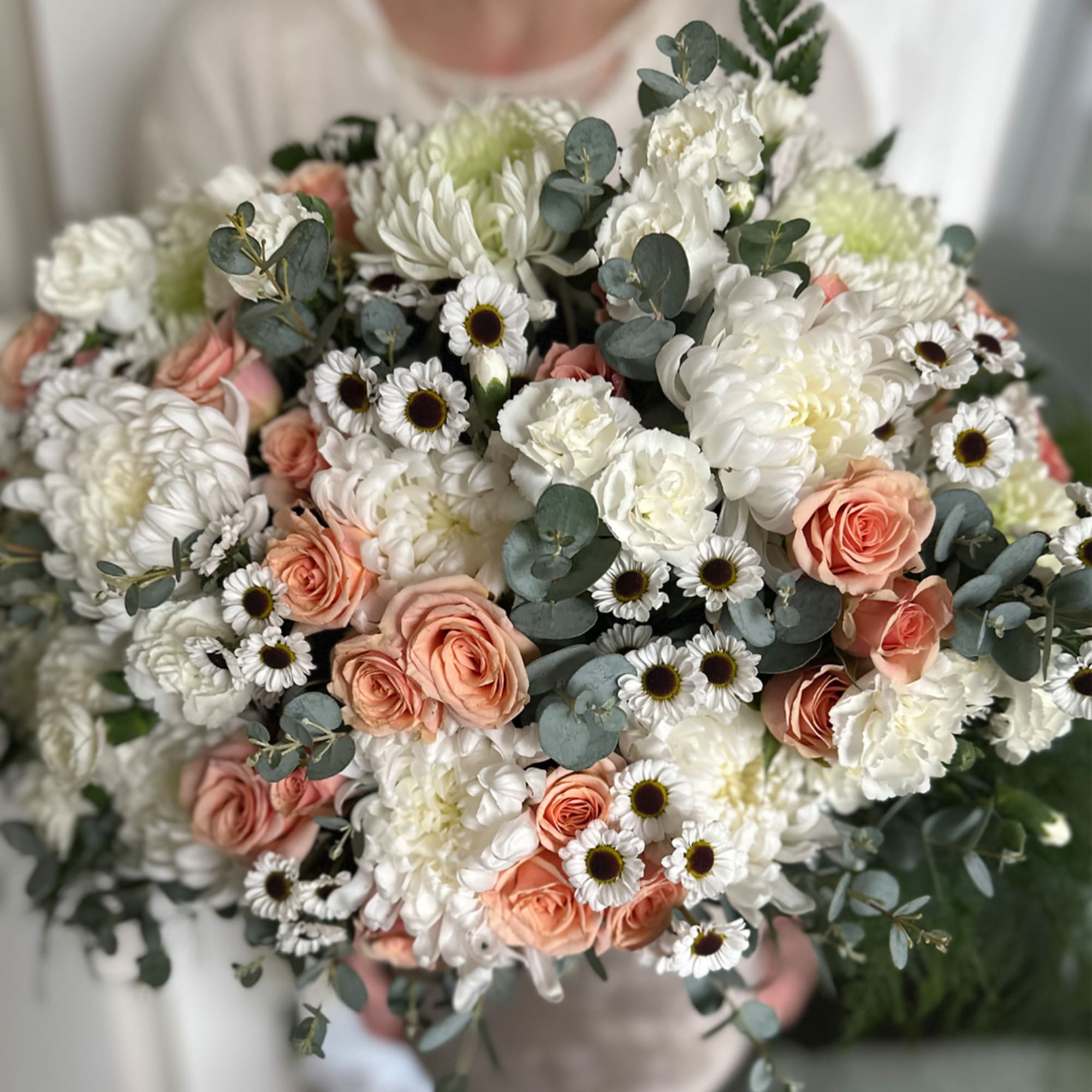 Bouquet of white and peach flowers with eucalyptus greenery