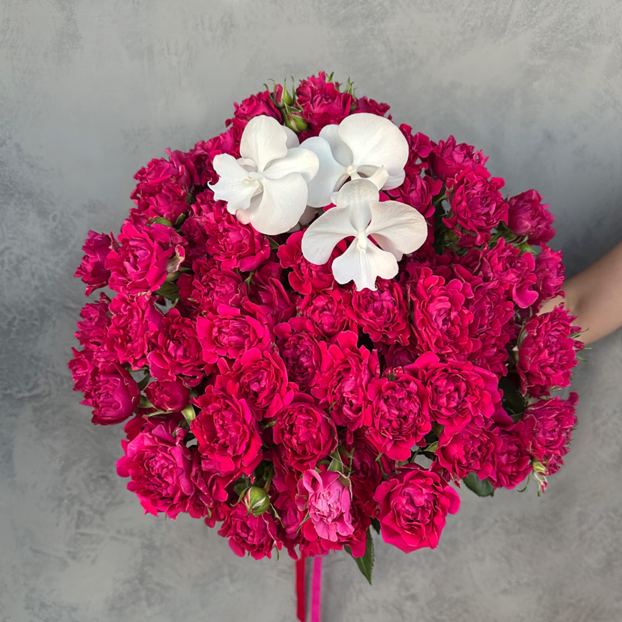 Round bouquet of hot pink roses with white orchids