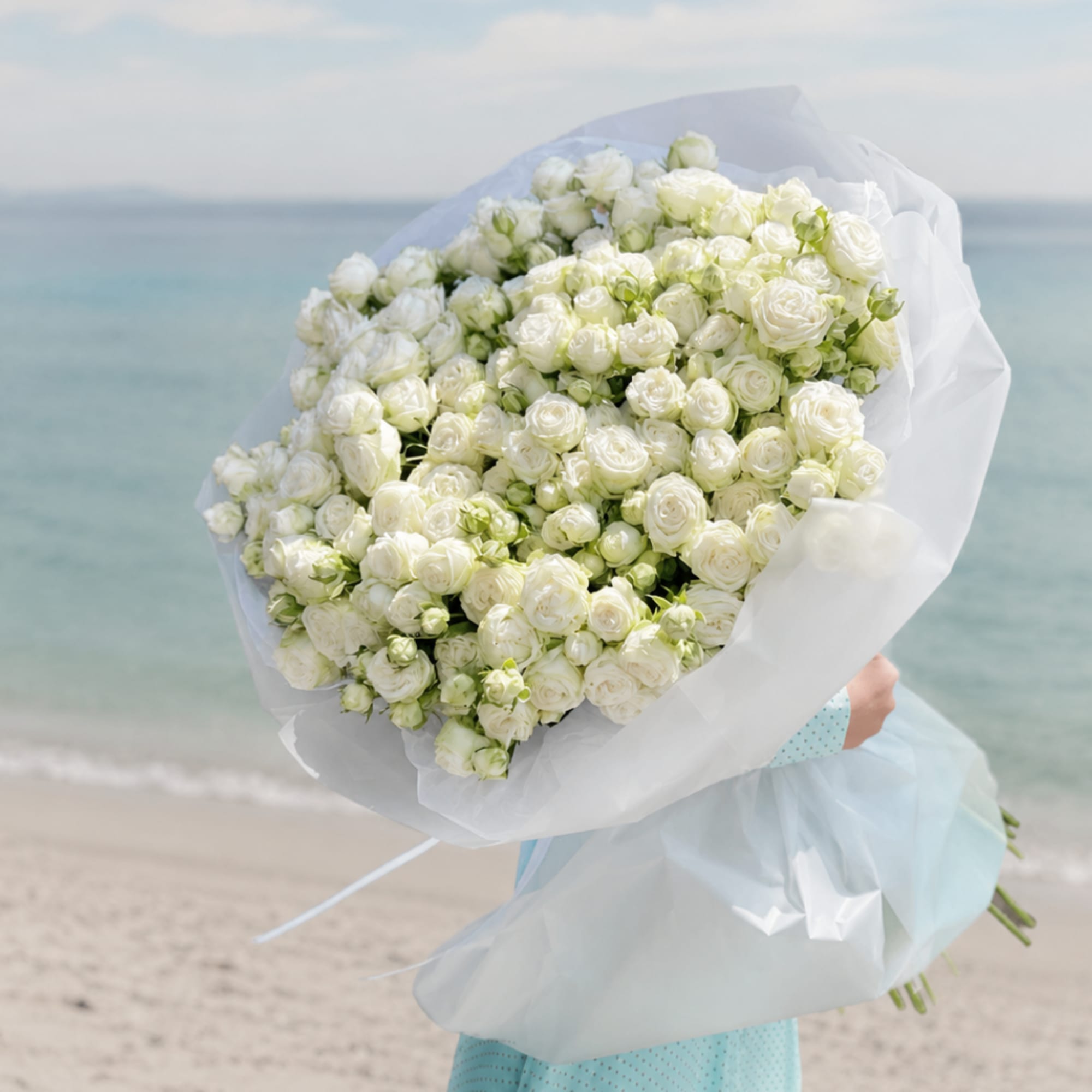 Large bouquet of white roses wrapped in white paper
