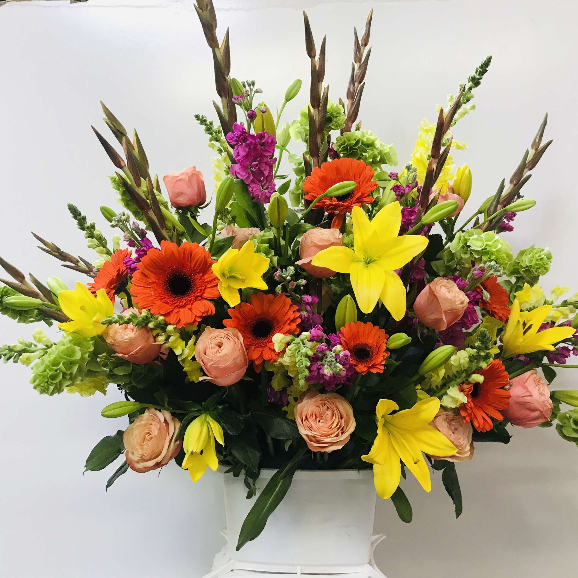 Bright mixed flower arrangement in a white container