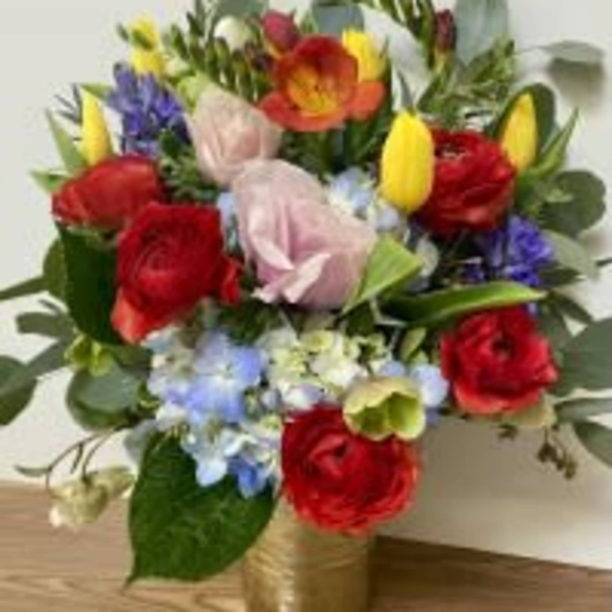 Colorful mixed bouquet in a gold vase with roses and tulips