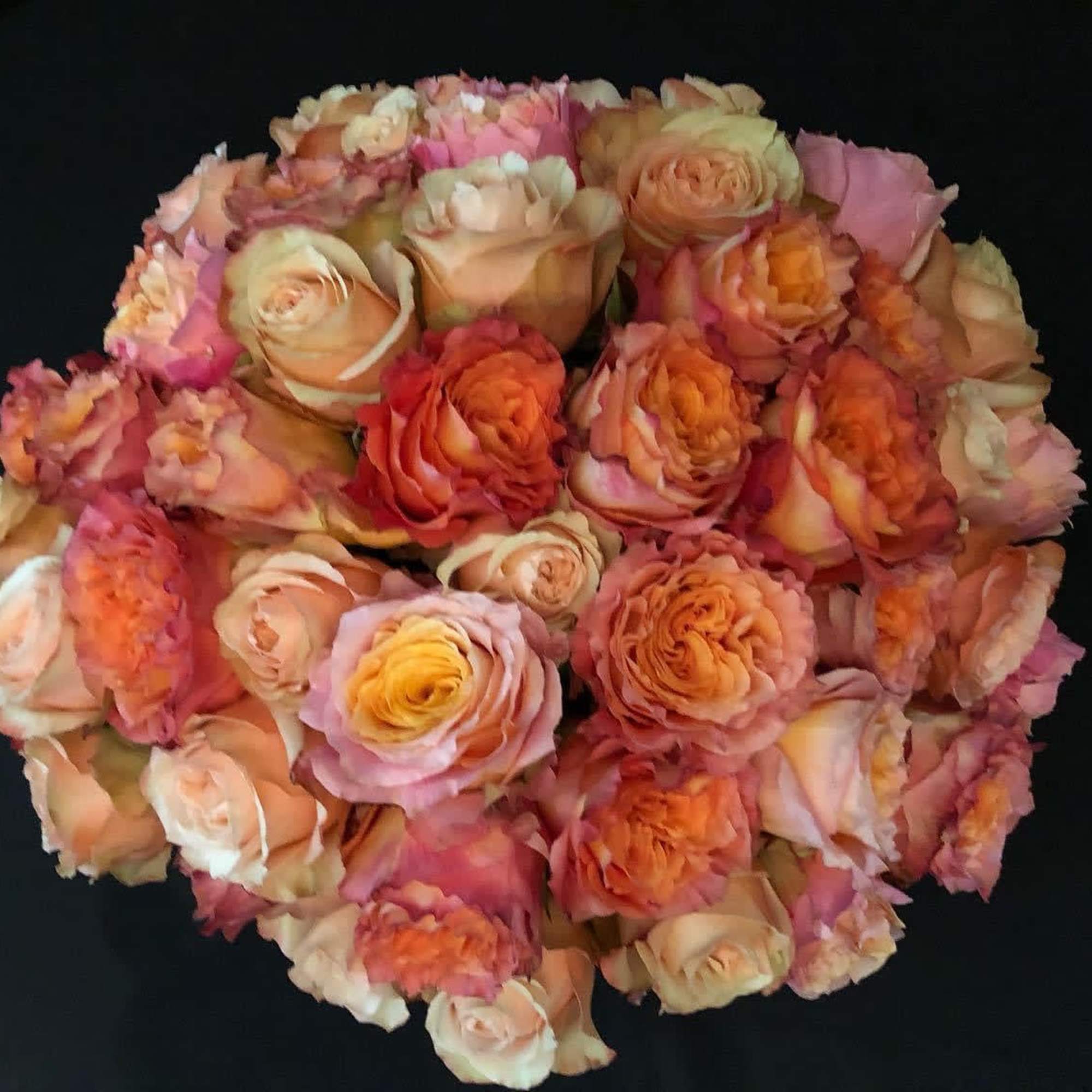 Round bouquet of peach, pink, and orange roses