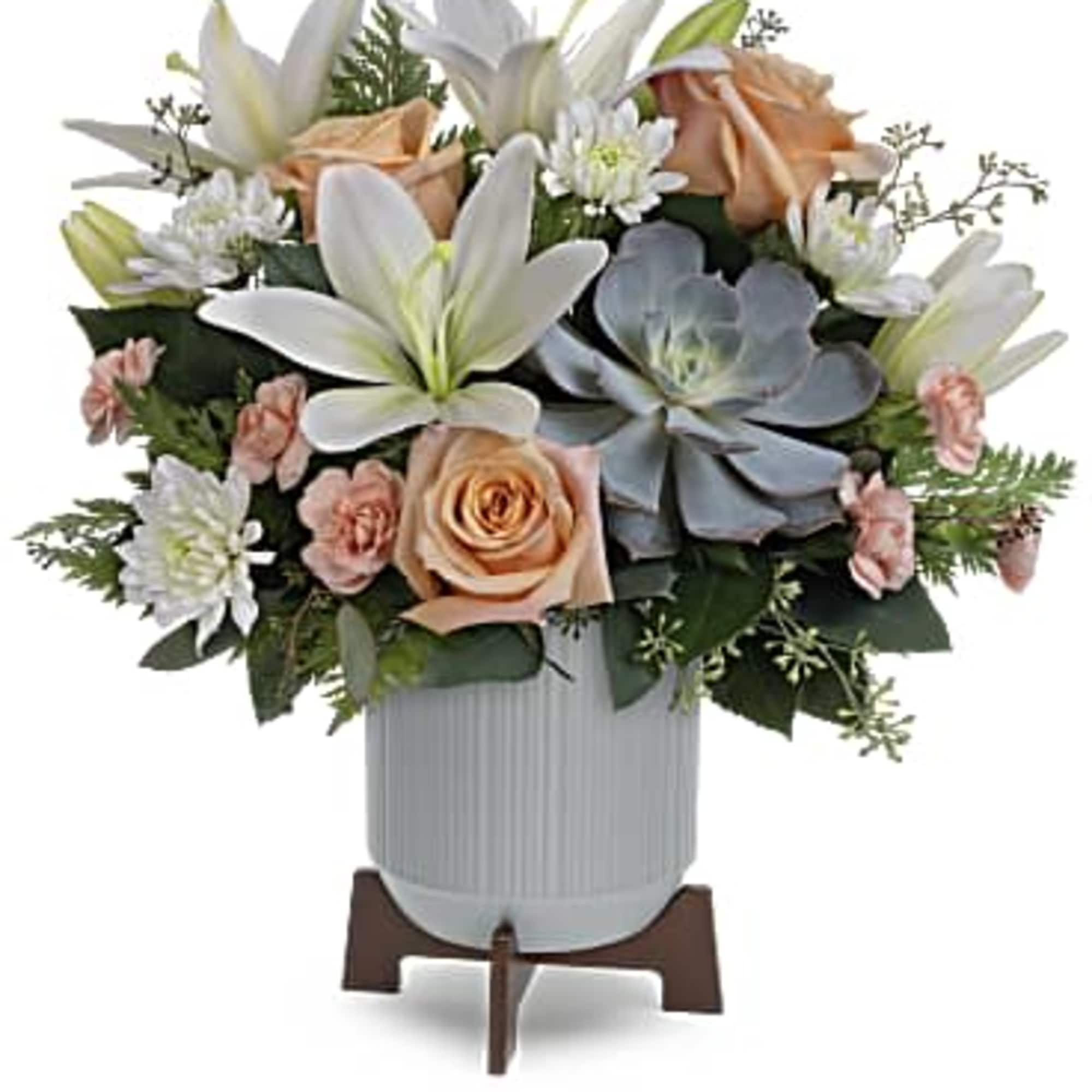 White lilies, peach roses, and succulents arranged in a white vase