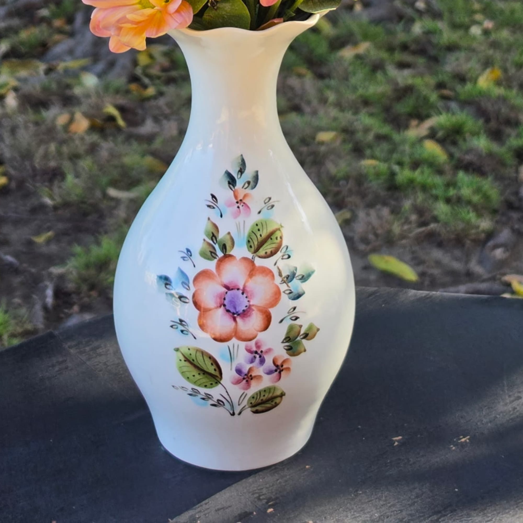 White vase with painted flowers and a peach flower at the top