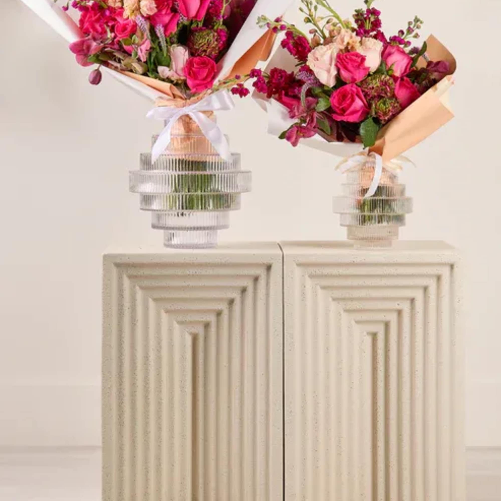 Two pink and magenta flower bouquets in clear ribbed vases