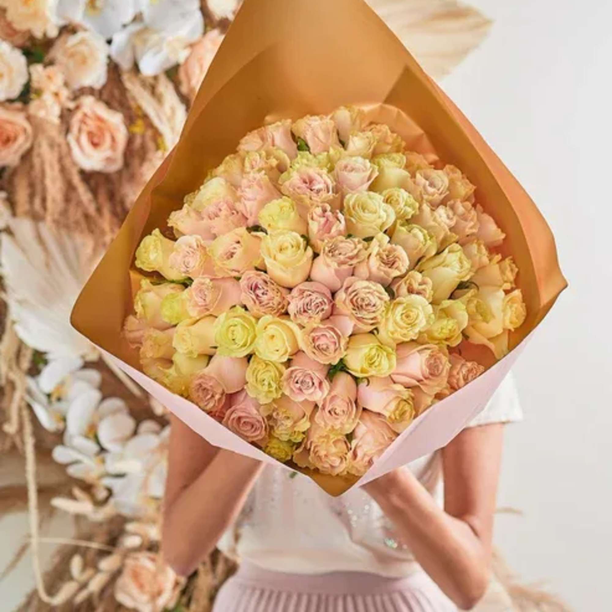 Large bouquet of pale pink and yellow roses wrapped in tan paper