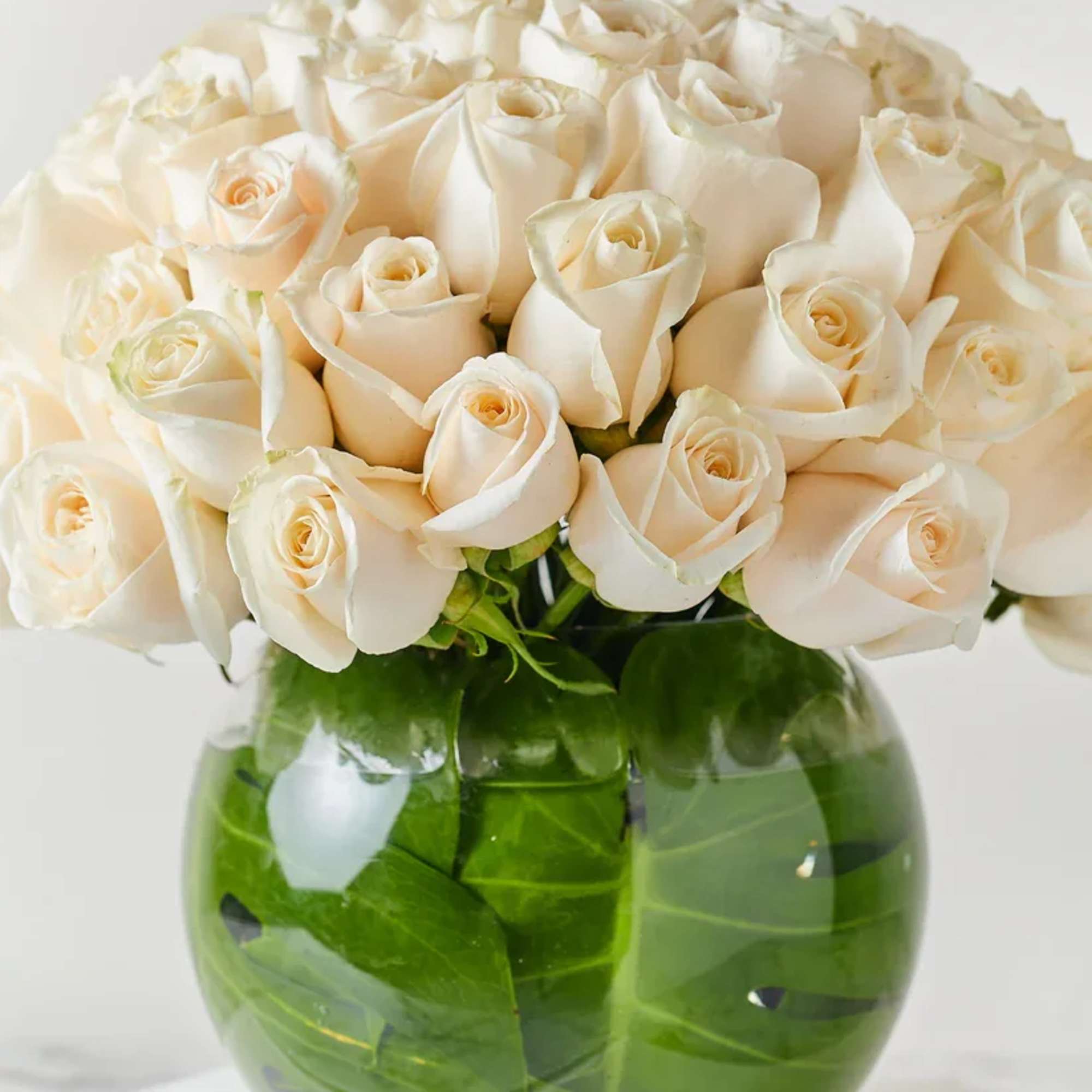 White rose bouquet in a round green glass vase