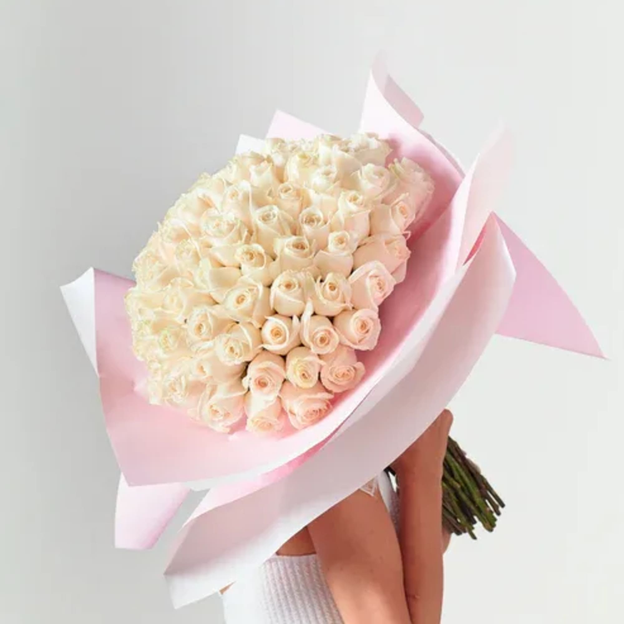Large bouquet of pale cream roses wrapped in pink paper