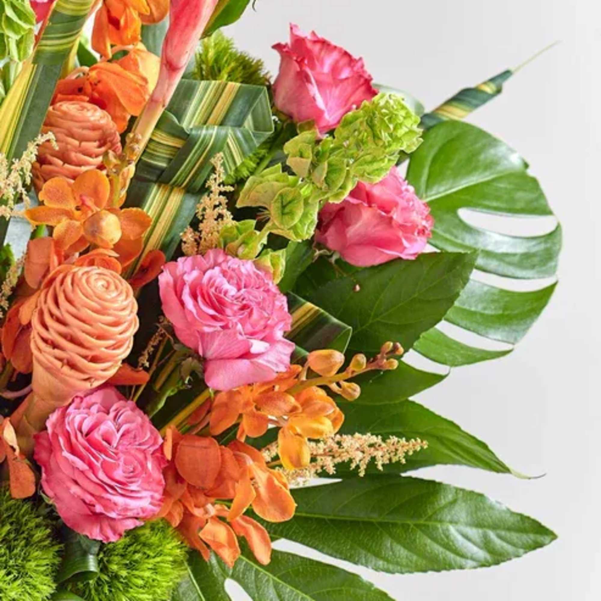 Tropical bouquet with pink and orange flowers and broad green leaves