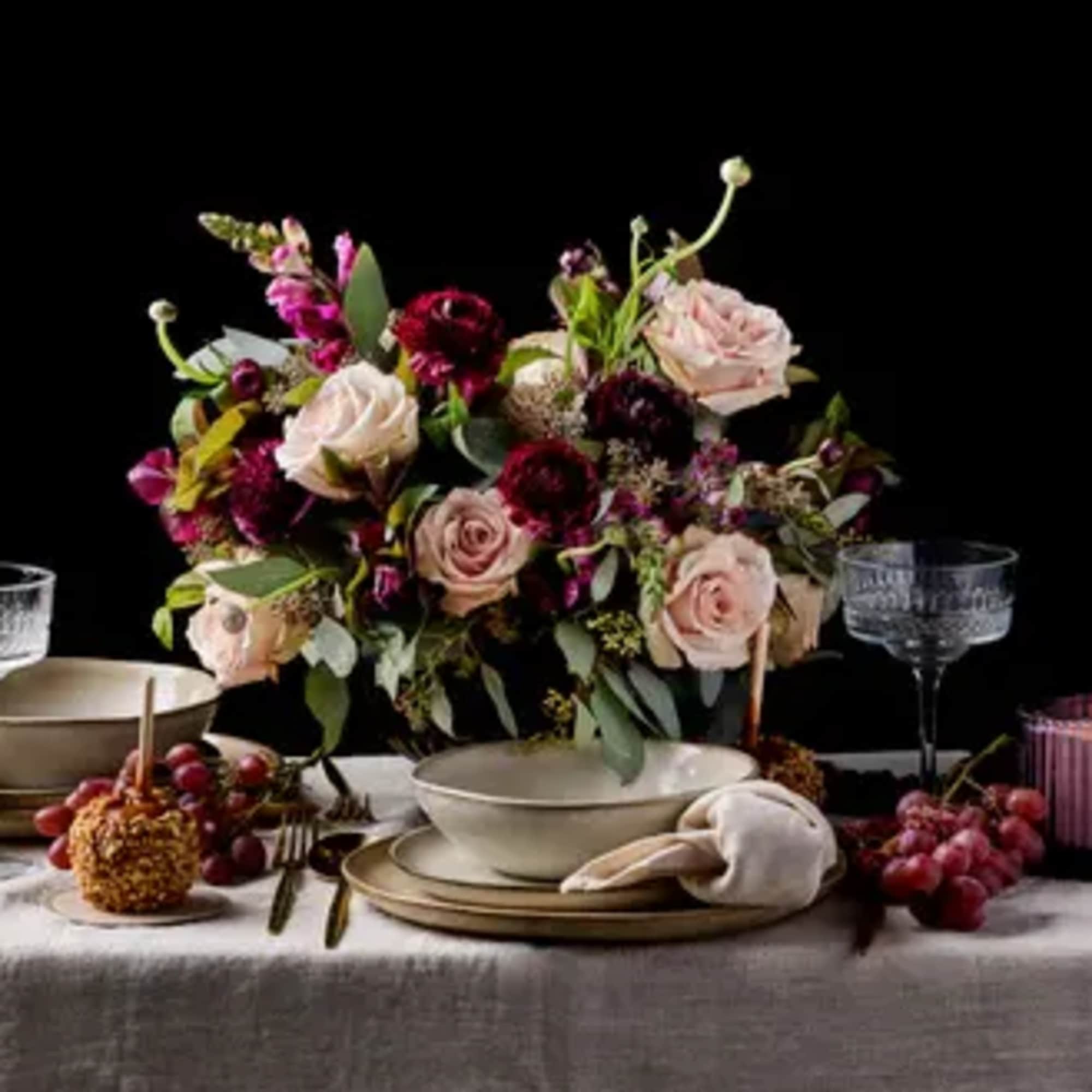 Floral centerpiece with pink and burgundy roses on a table setting