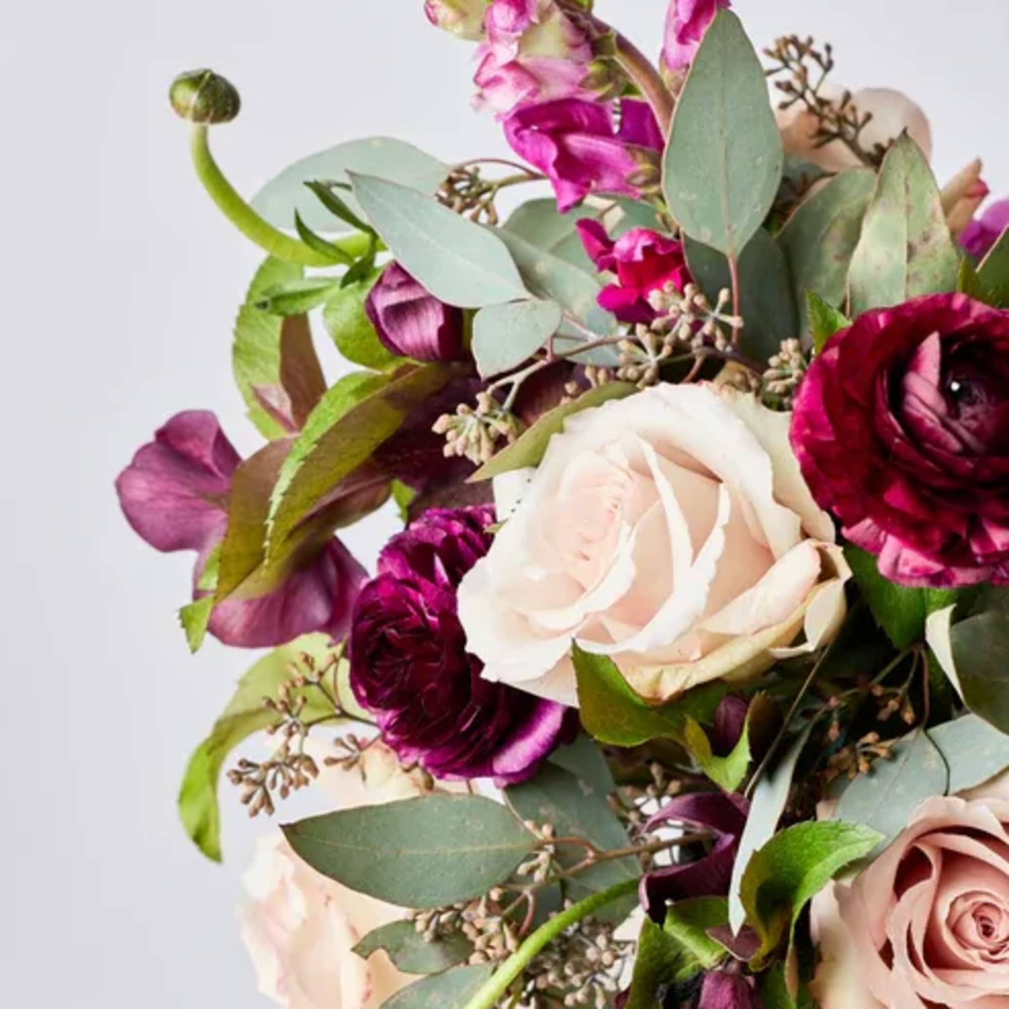 Bouquet of blush and deep magenta flowers with eucalyptus in a vase