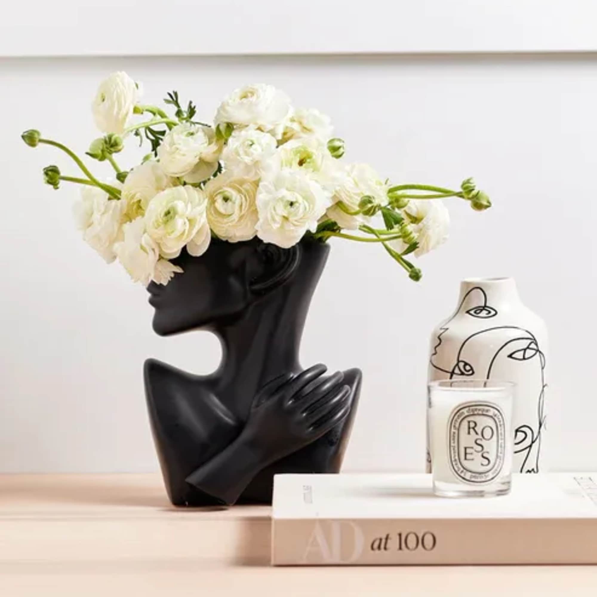 White ranunculus arrangement in a black sculptural vase