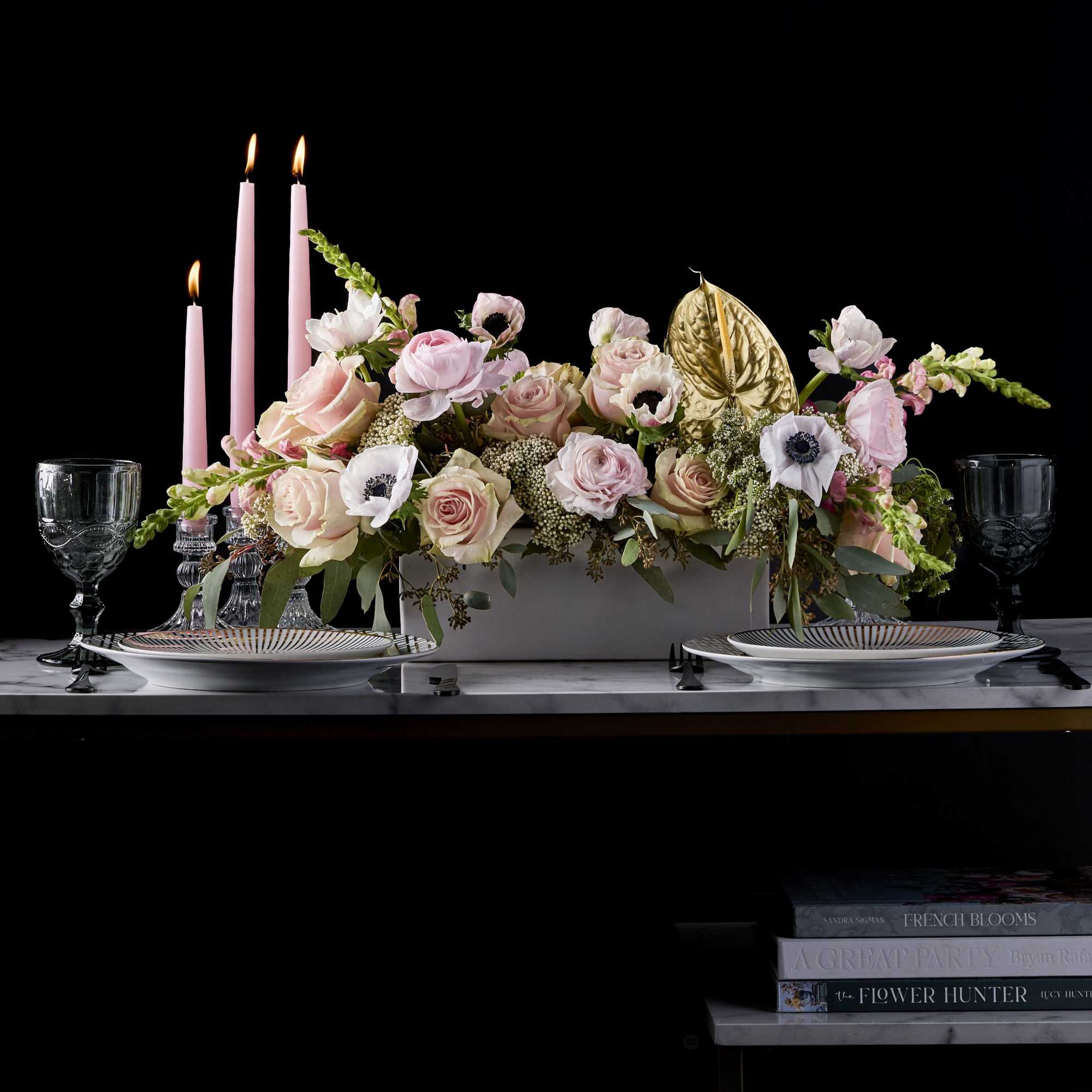 Pink floral centerpiece with candles and gold accent on a table