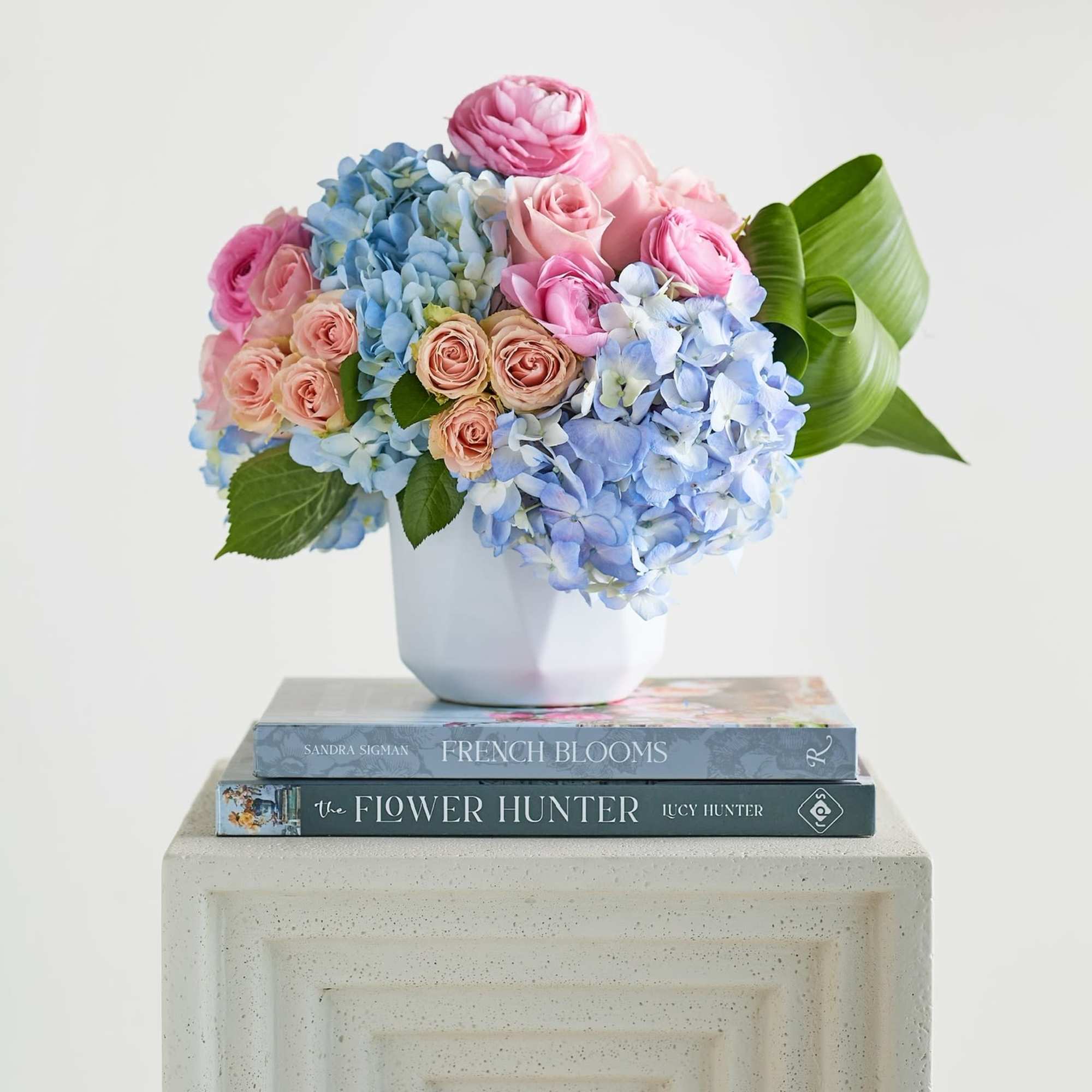 Pink roses and blue hydrangeas in a white vase
