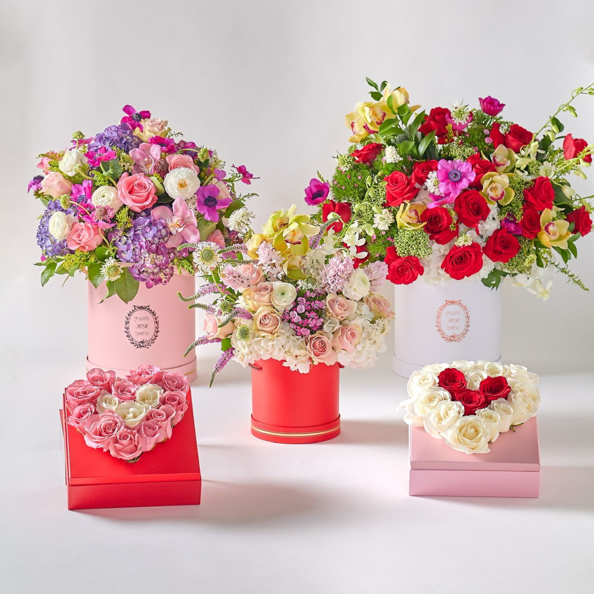Four floral gift boxes with roses and mixed blooms in pink, red, and white.