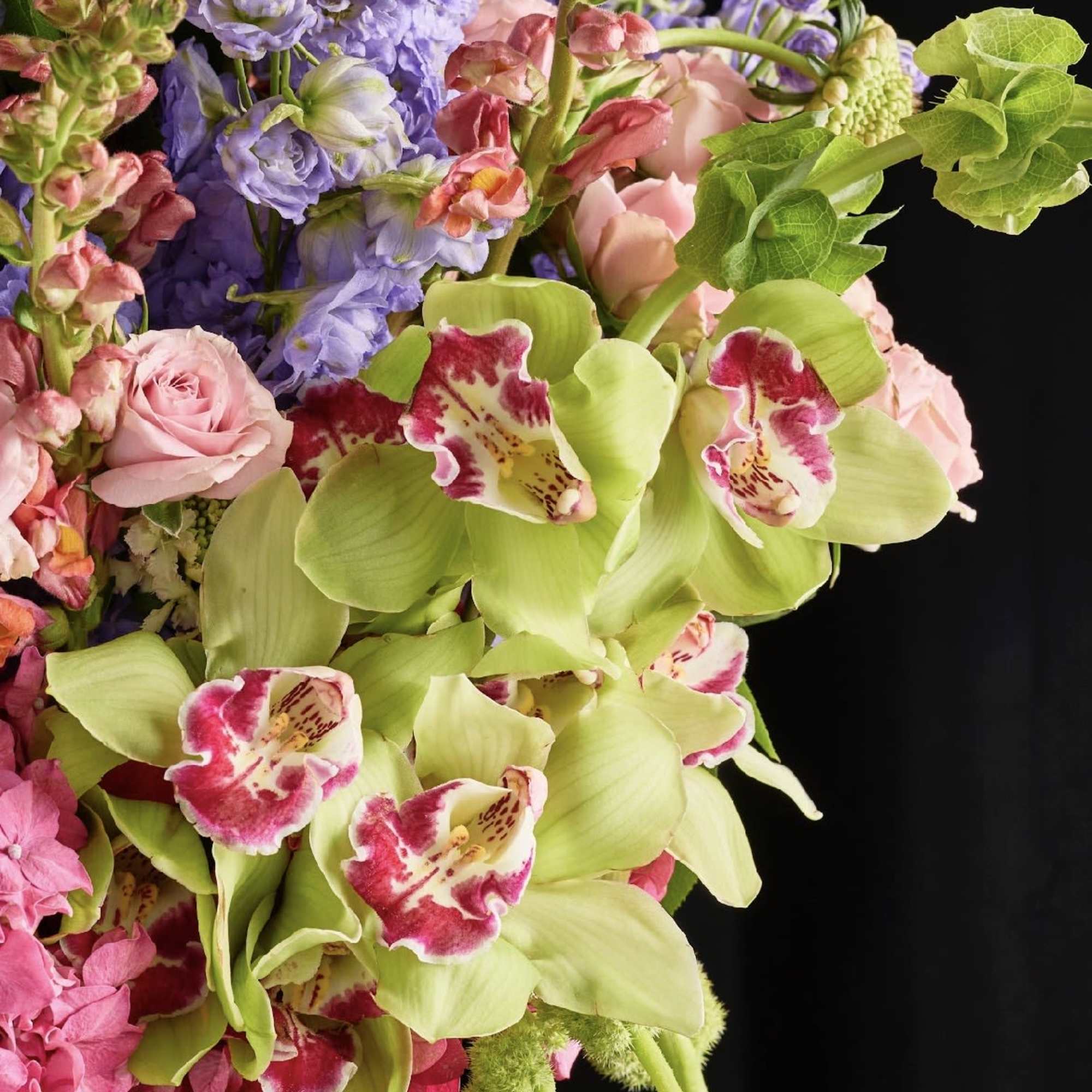 Bouquet of green orchids, pink roses, and purple flowers
