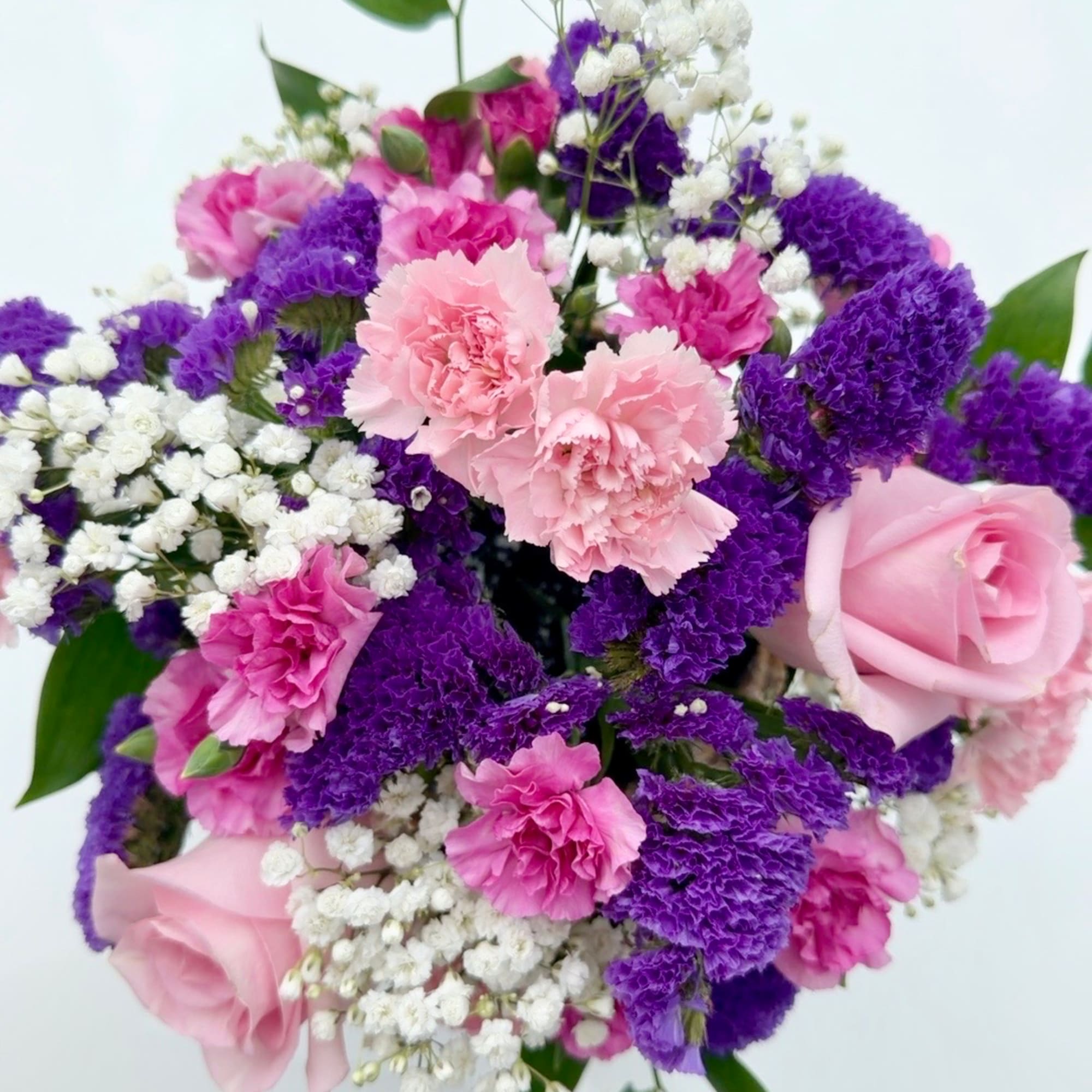 Bouquet of pink roses, carnations, and purple filler flowers