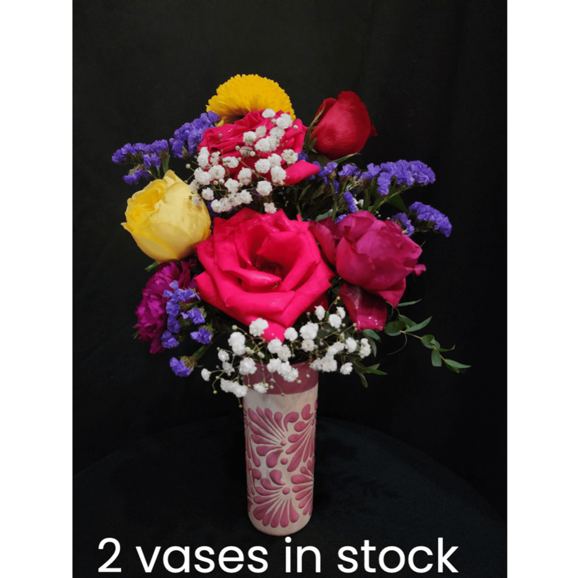 Colorful rose bouquet in a patterned vase against a black background