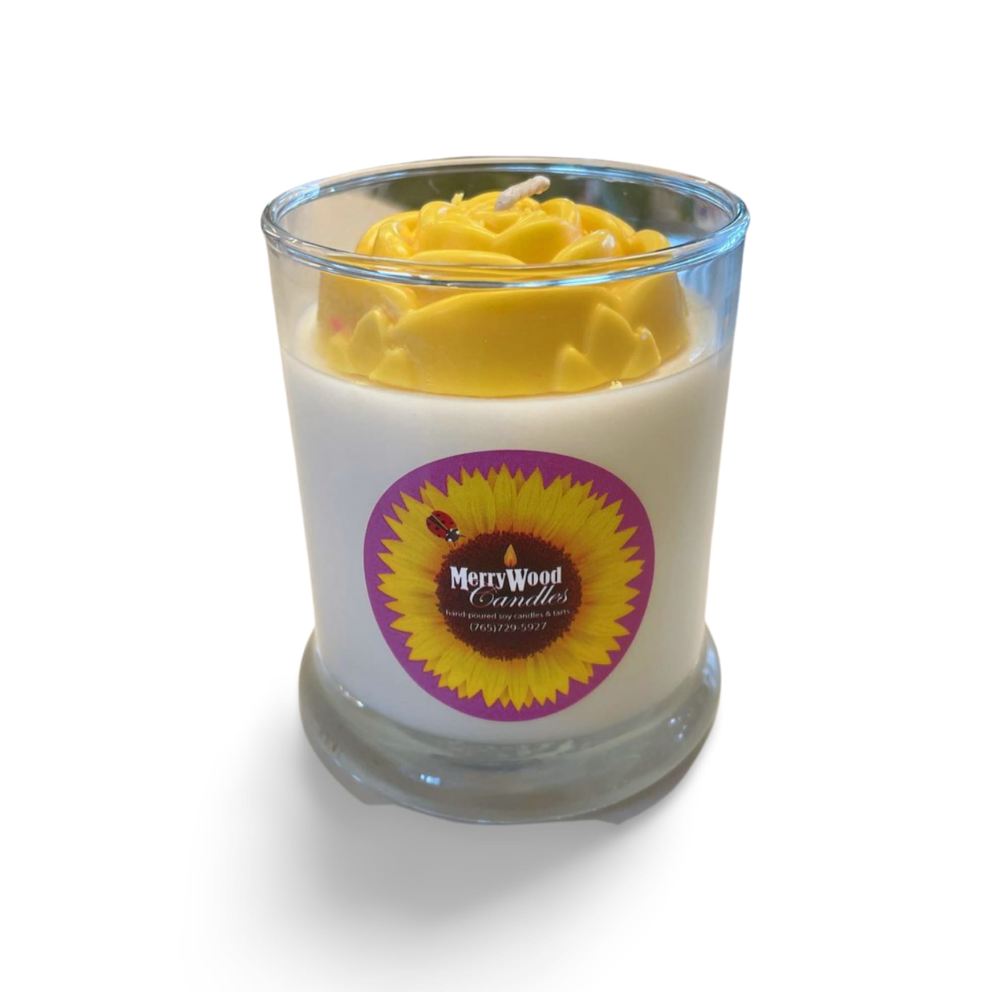 Yellow candle in a clear glass tumbler with a sunflower label