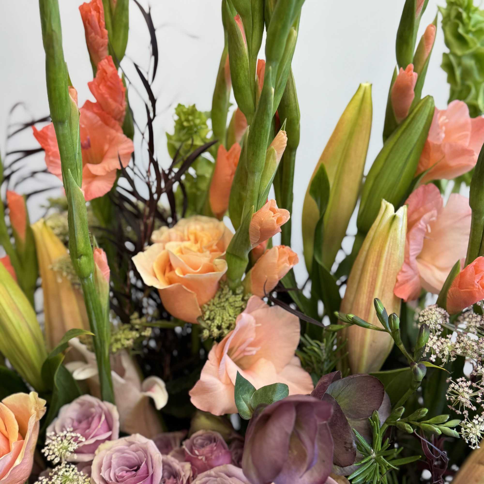 Bouquet of peach, lavender, and pink flowers with tall green stems